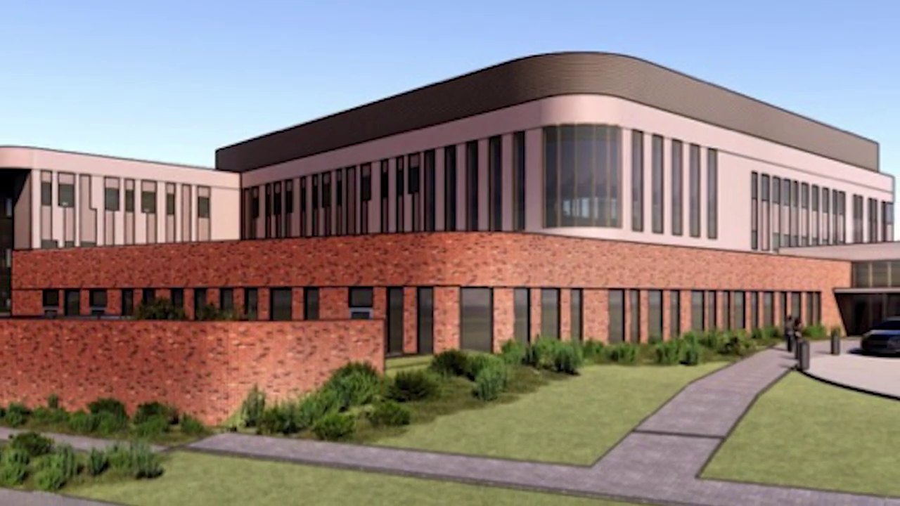 Architectural rendering of a modern two-story brick and glass medical building with landscaped grounds.
