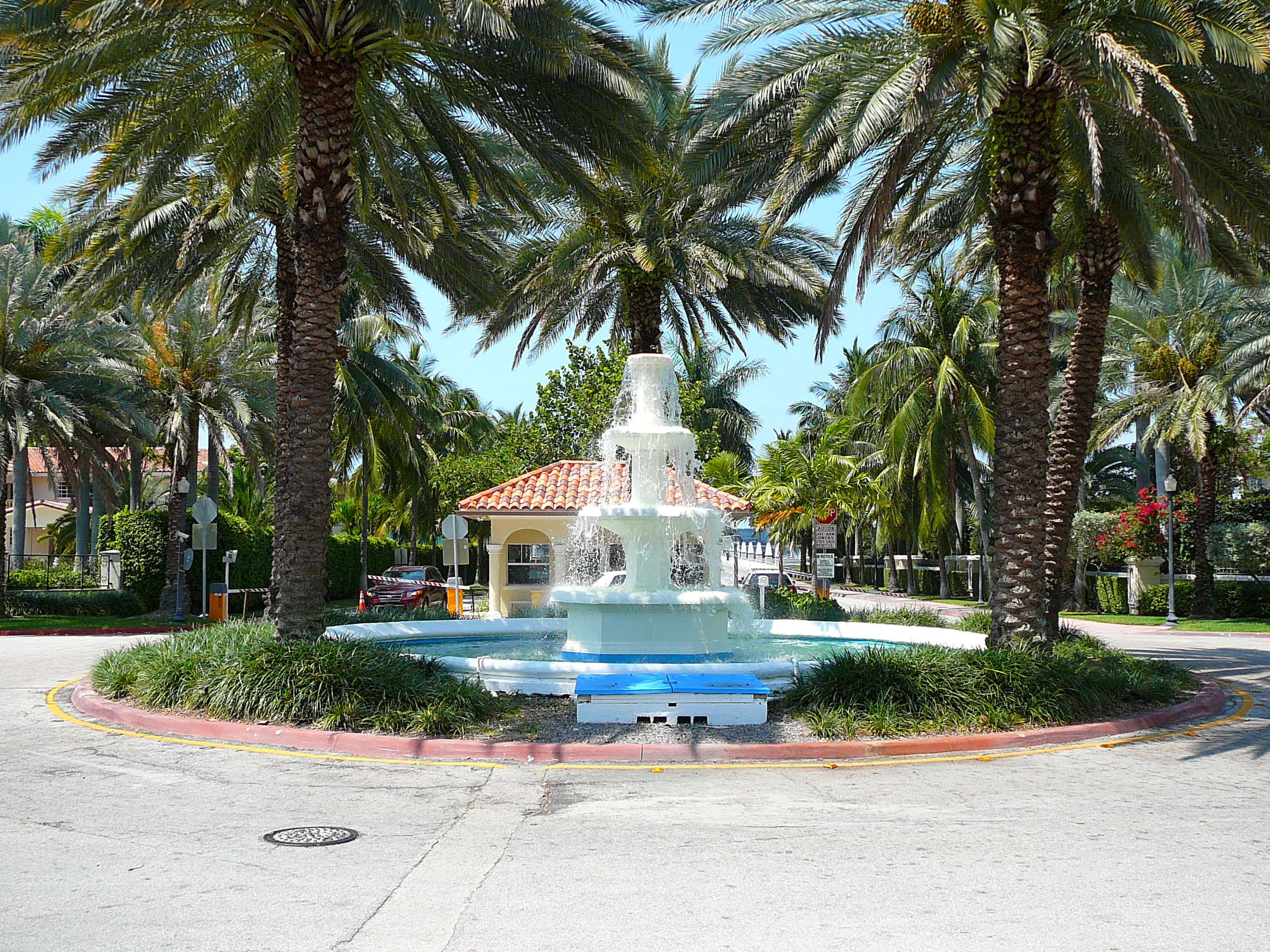 White tiered fountain in a landscaped roundabout at the Palm Island guard gate entrance.
