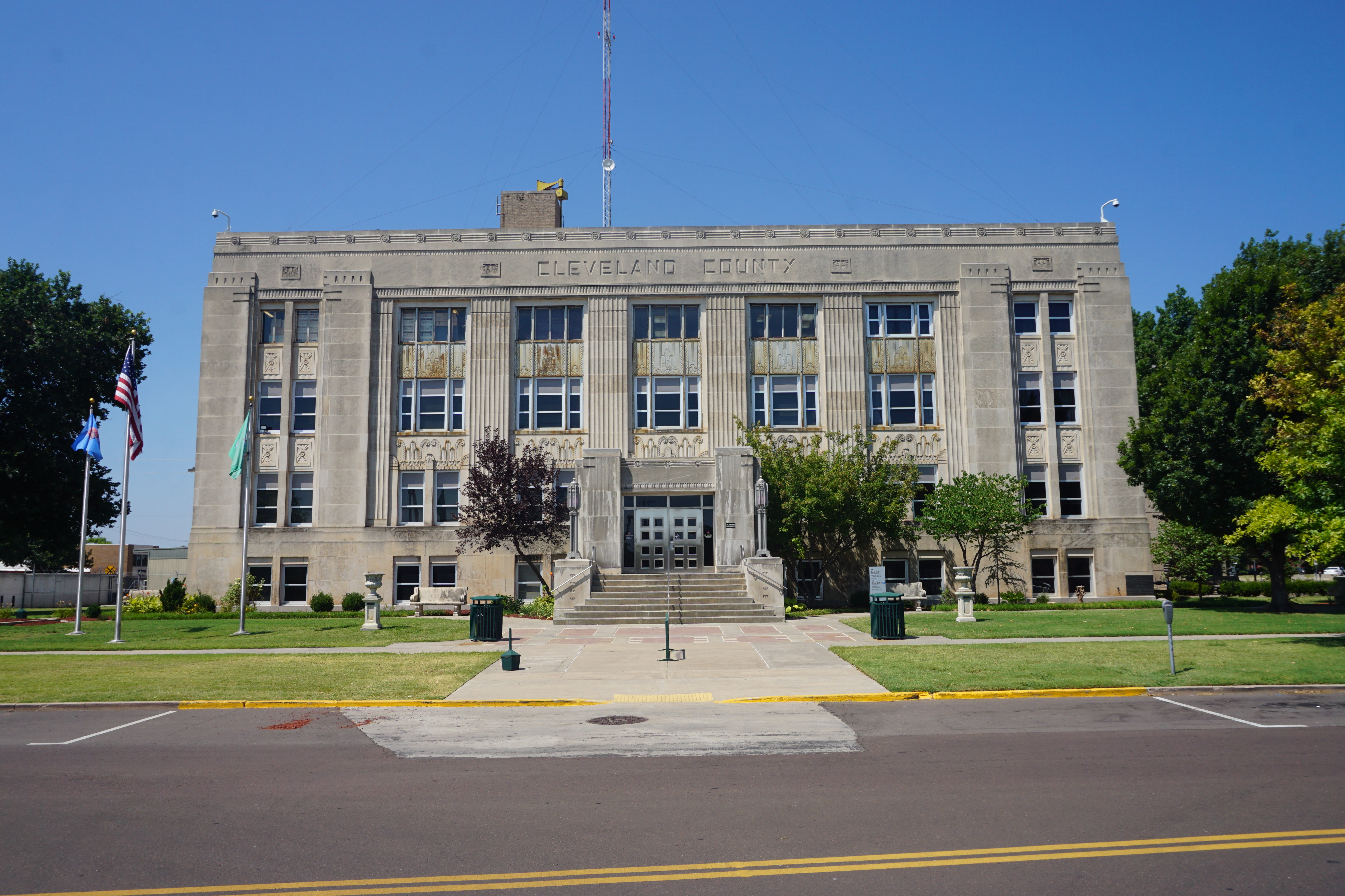 Stone Art Deco government building labeled Cleveland County under a clear blue sky.
