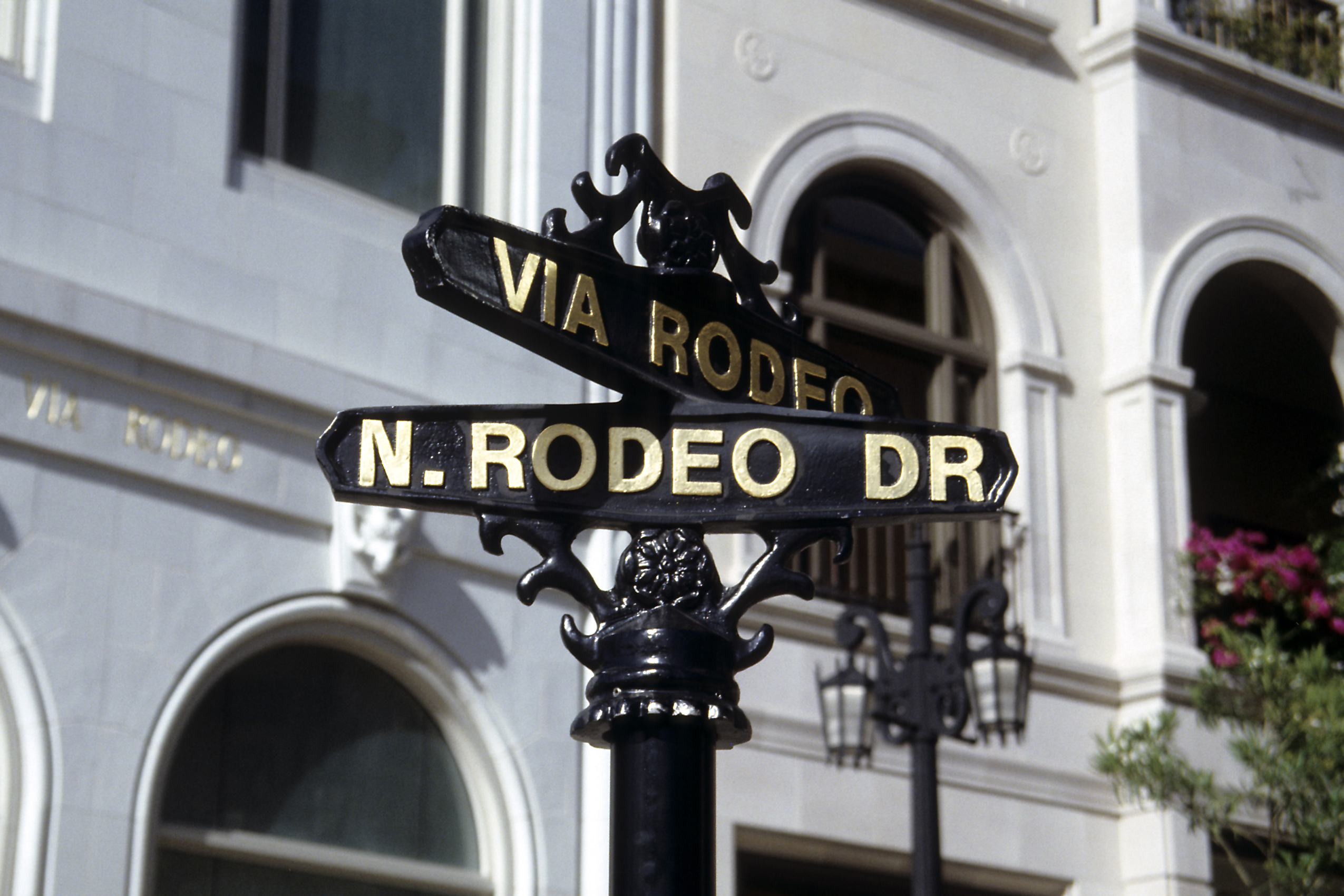 Ornate black and gold street sign at the Via Rodeo and Rodeo Drive intersection.