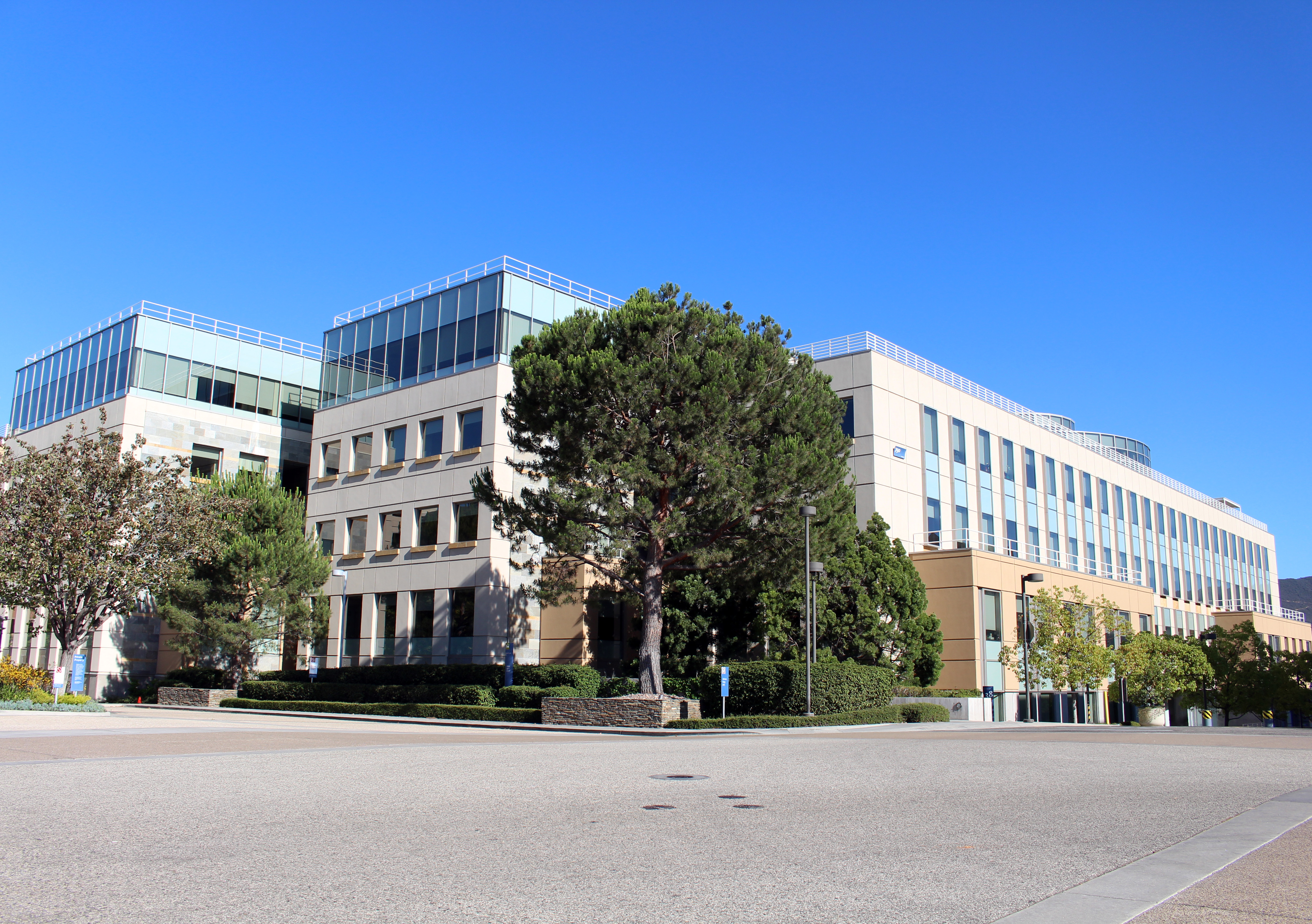 Multi-story glass and concrete office buildings on a corporate campus surrounded by trees.
