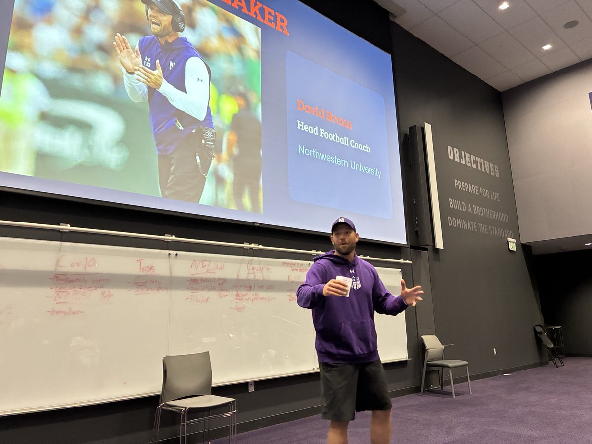 Man in purple Northwestern hoodie speaks at a podium before a projected slide.