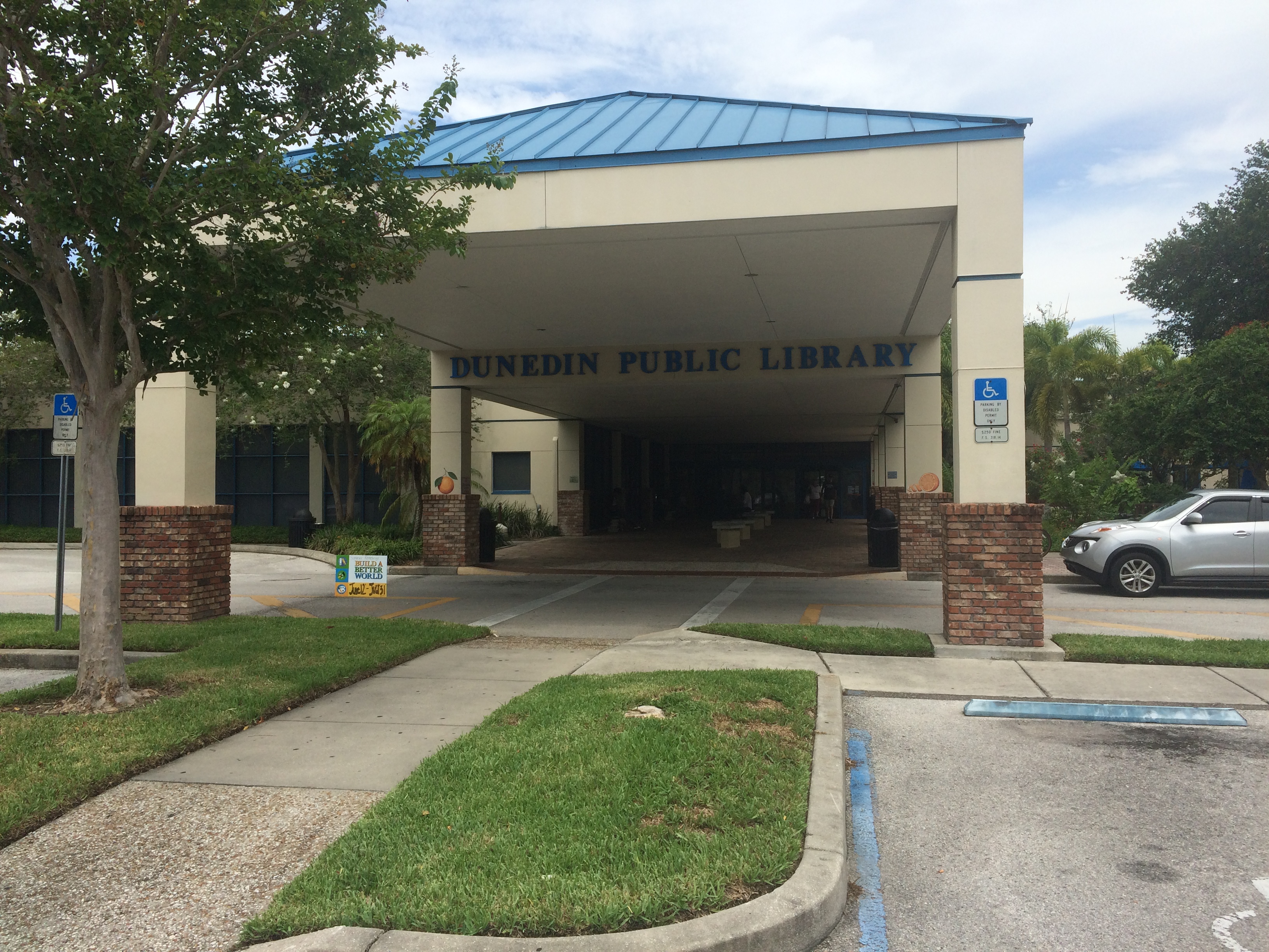 Exterior entrance of the Dunedin Public Library with a blue metal roof canopy.