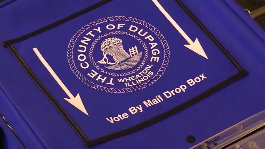 Blue vote-by-mail drop box with County of DuPage seal and white arrows pointing to the mail slot.