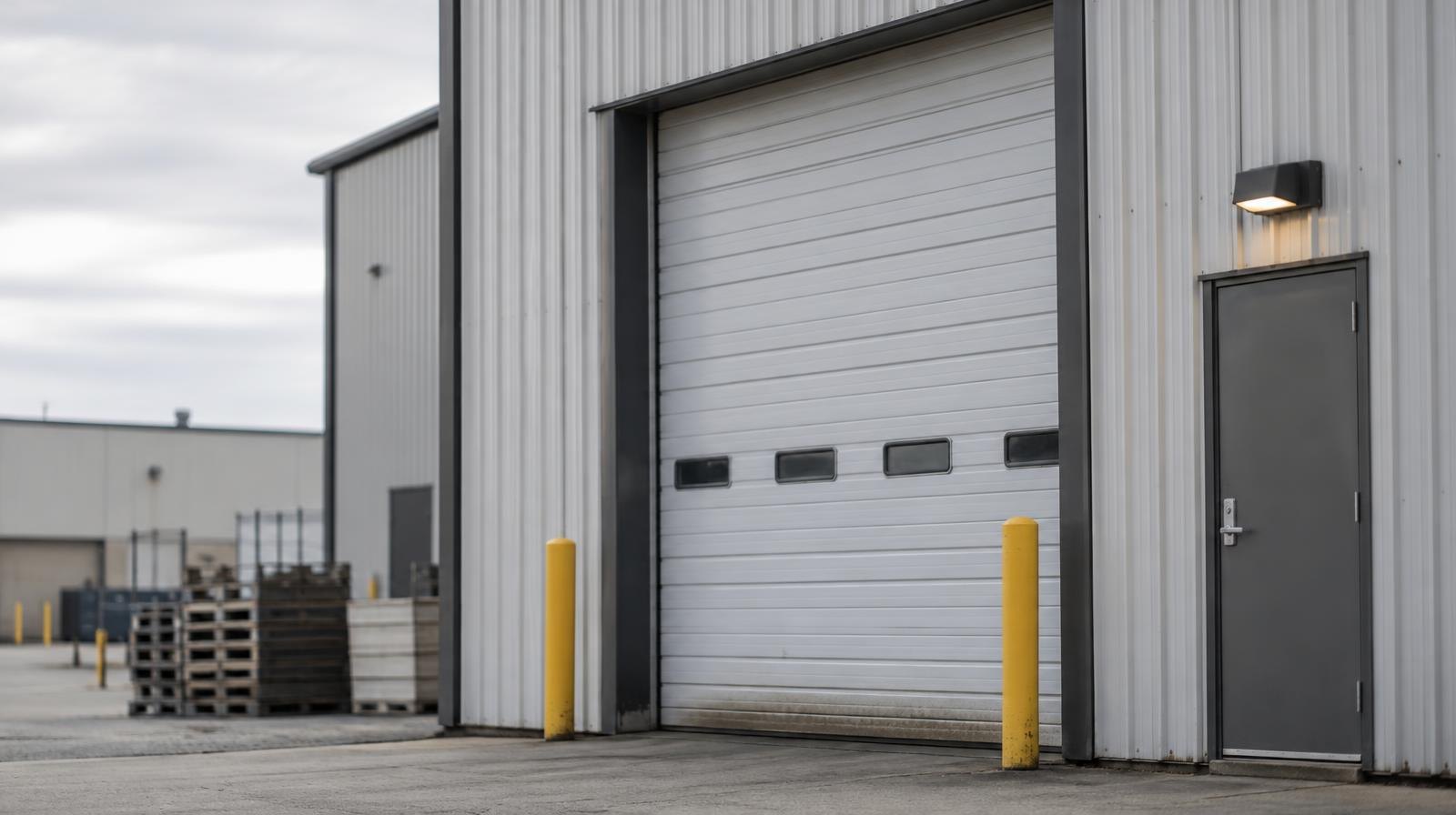 Large corrugated steel industrial building with a wide roll-up loading bay door.