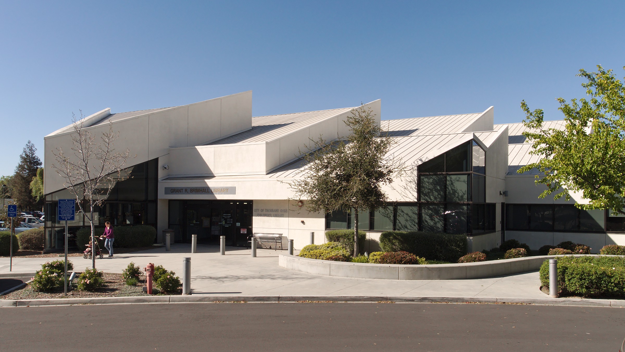 Modern public library exterior with angular white roof panels and large glass windows.