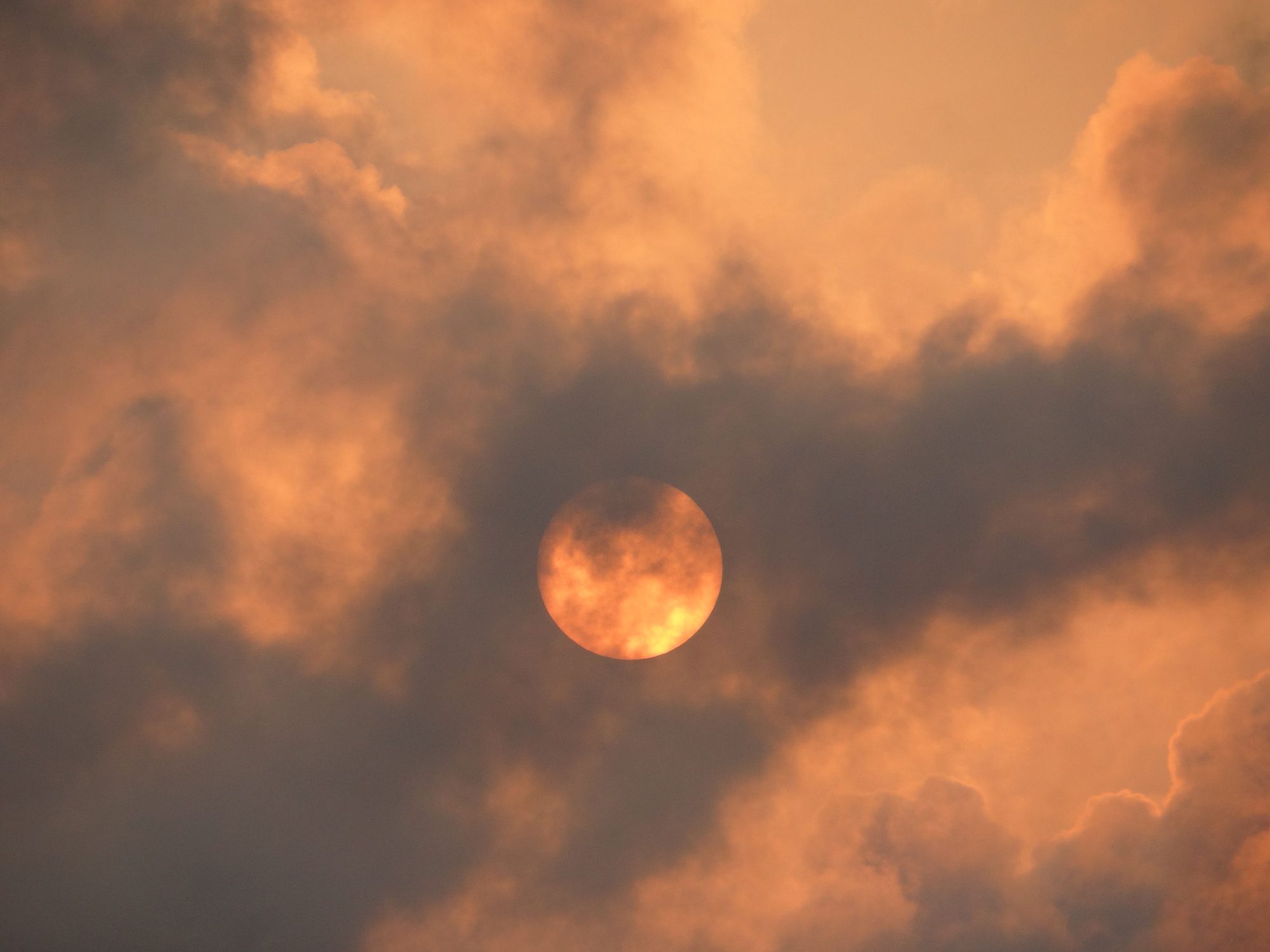 A dramatic cloudscape with the sun casting warm hues, creating a striking visual contrast in the sky.