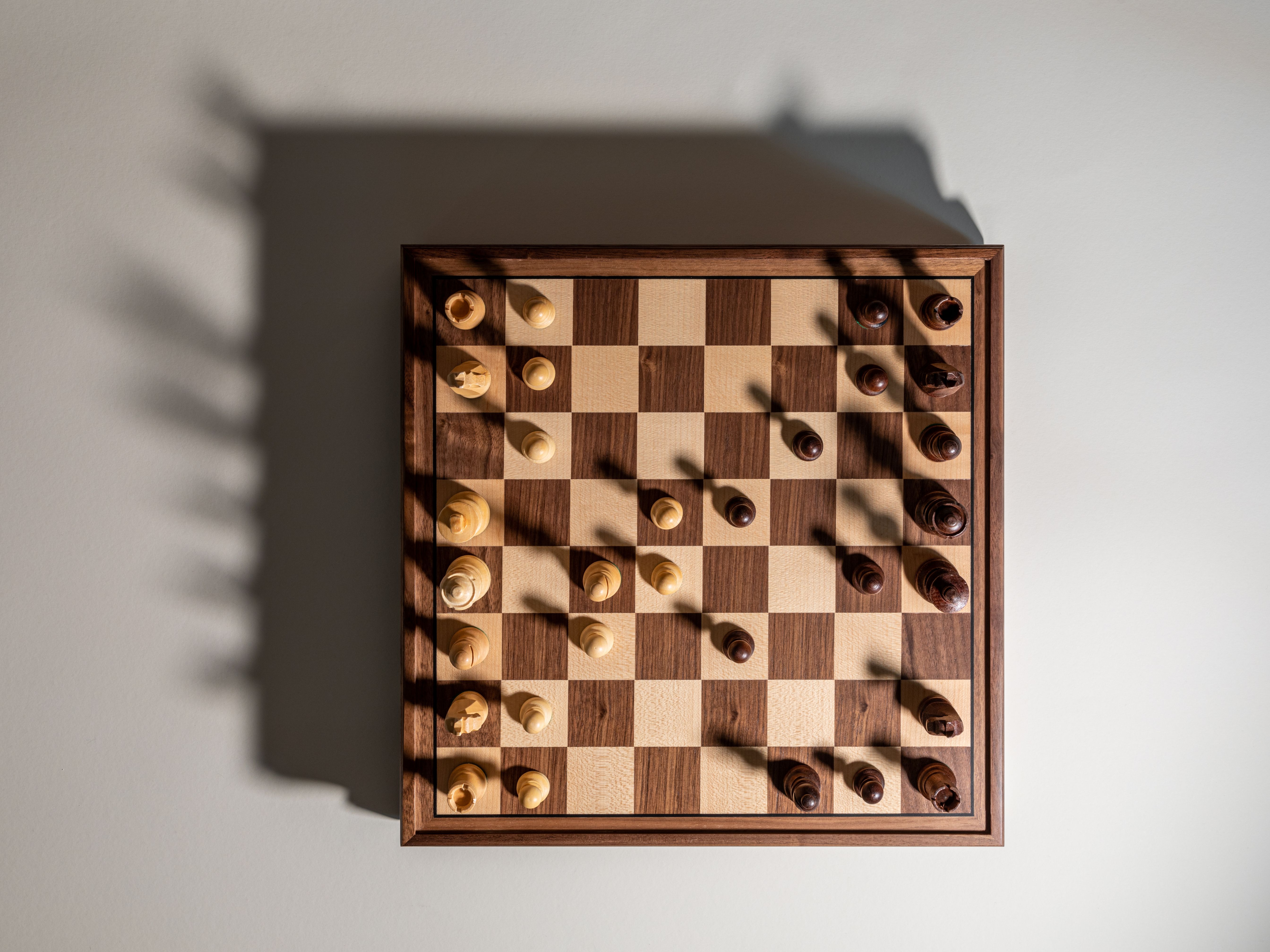 Chess board with wooden pieces arranged mid-game, viewed from above.