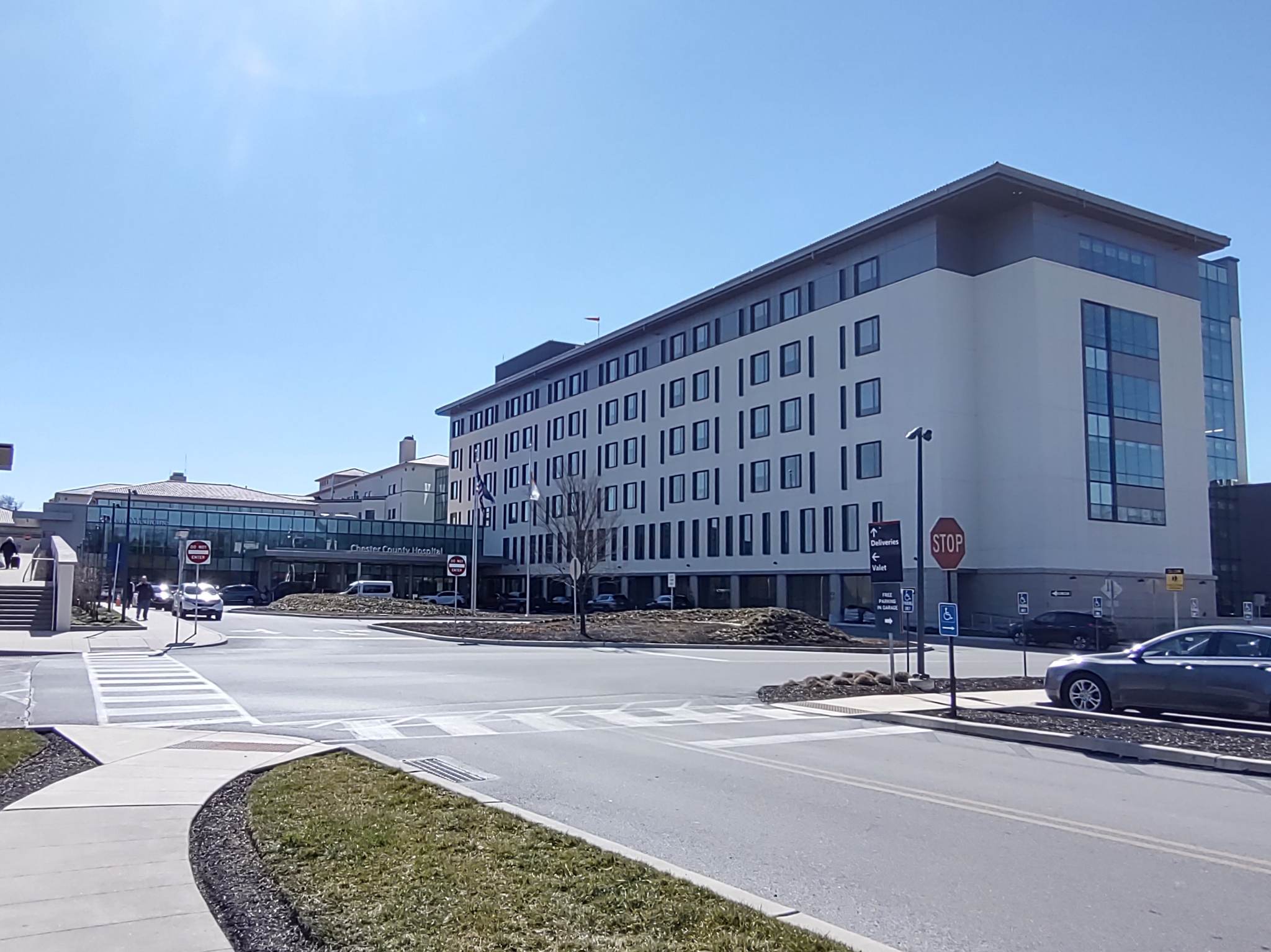 Modern multi-story hospital building at a street intersection on a sunny day.