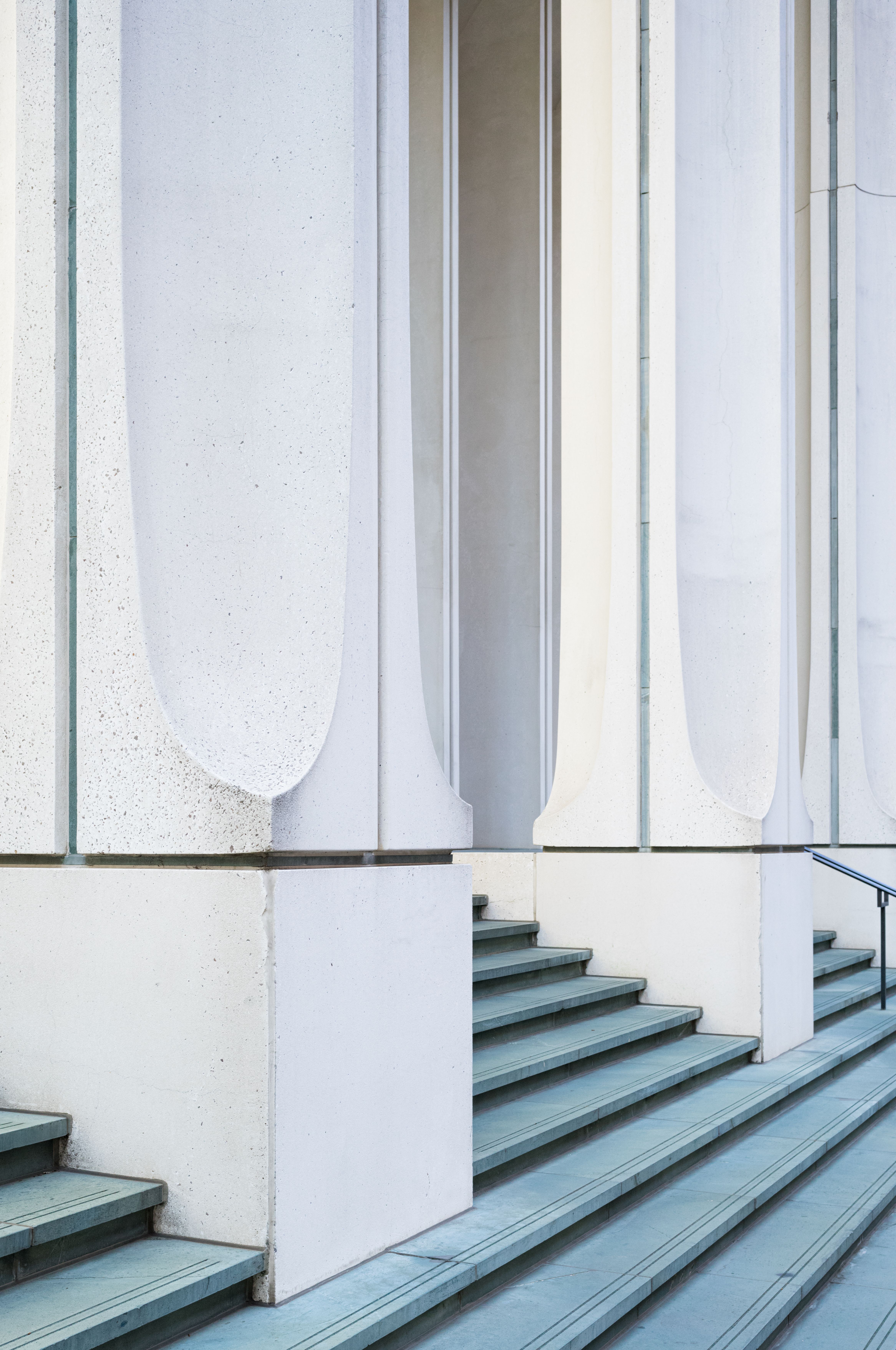 Wide concrete steps and tall white columns at the entrance of a modernist office building.