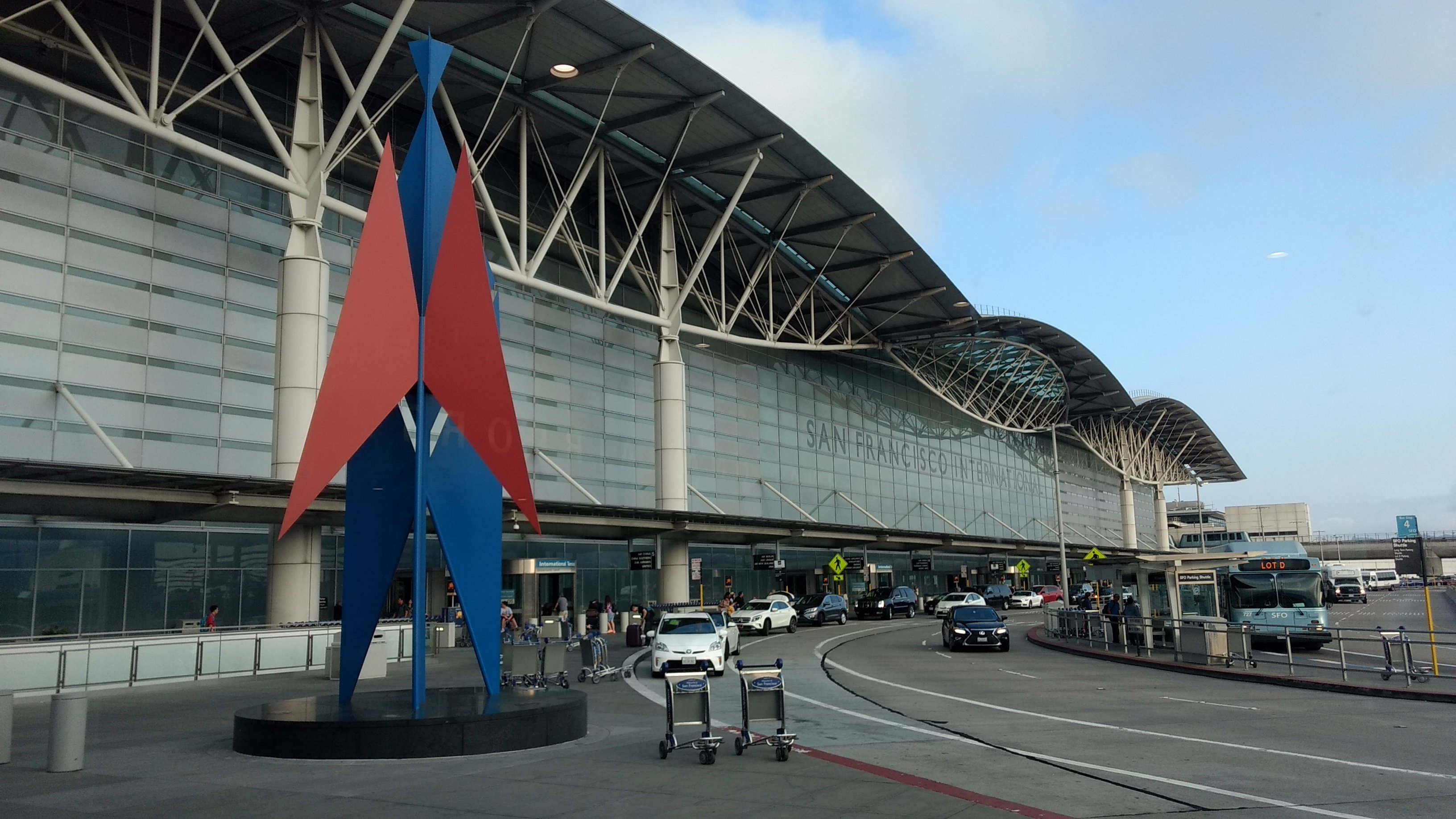 Exterior of an airport international terminal with a colorful abstract sculpture in the foreground.