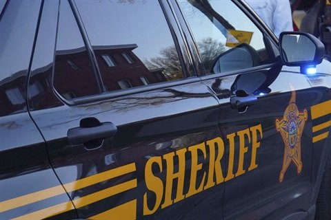 Close-up of a dark-colored sheriff's office SUV door with gold lettering and star badge emblem.