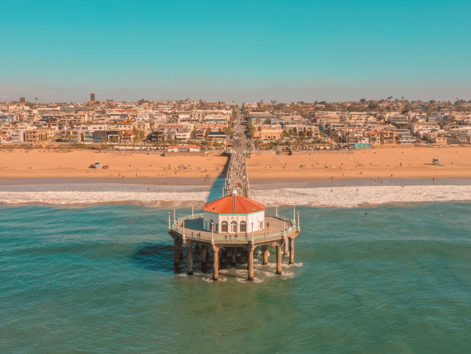 A stunning aerial view of the Manhattan Beach Pier extending over the ocean with cityscape in the background.