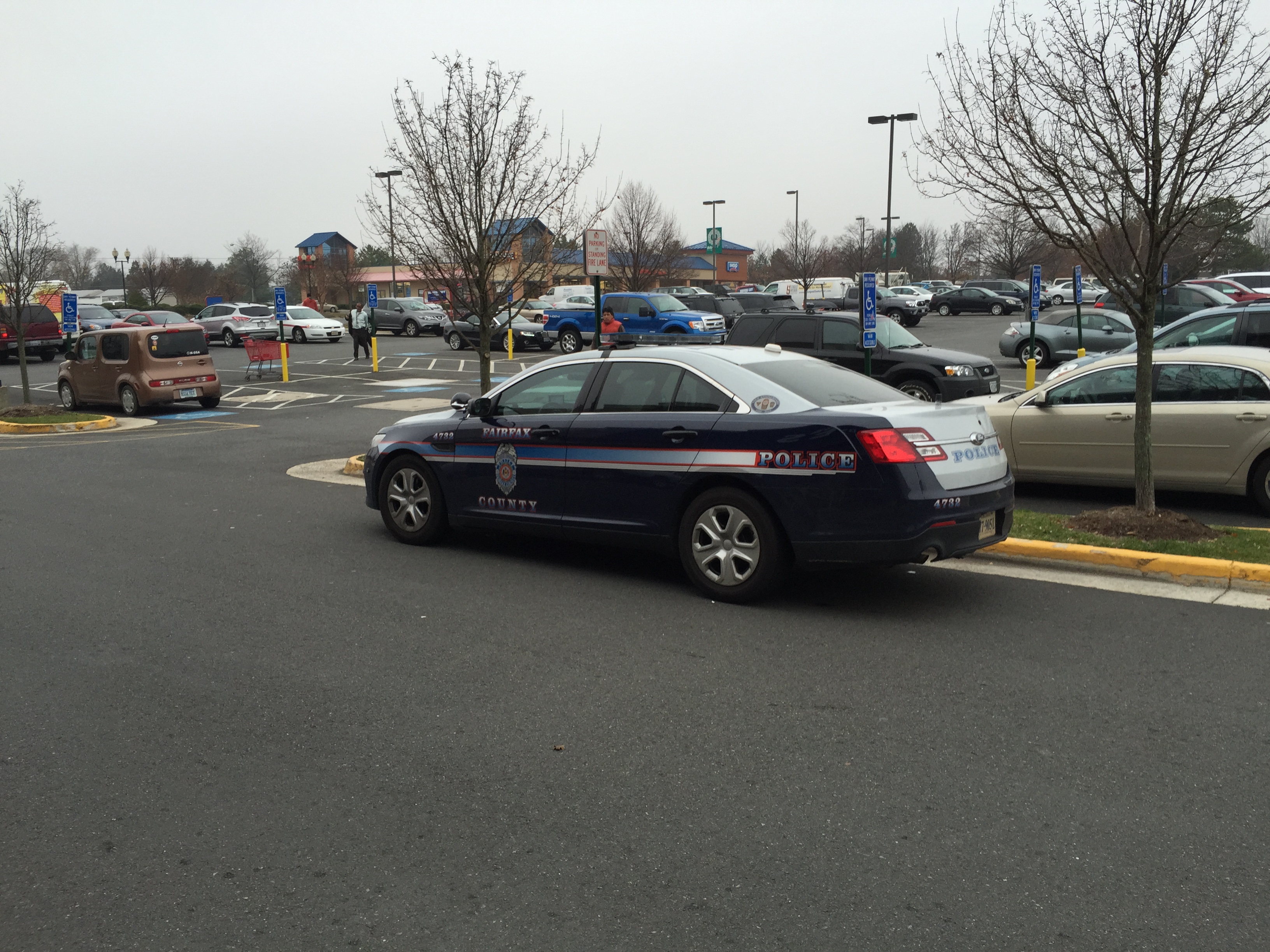A marked Fairfax County Police patrol car parked in a lot on an overcast day.