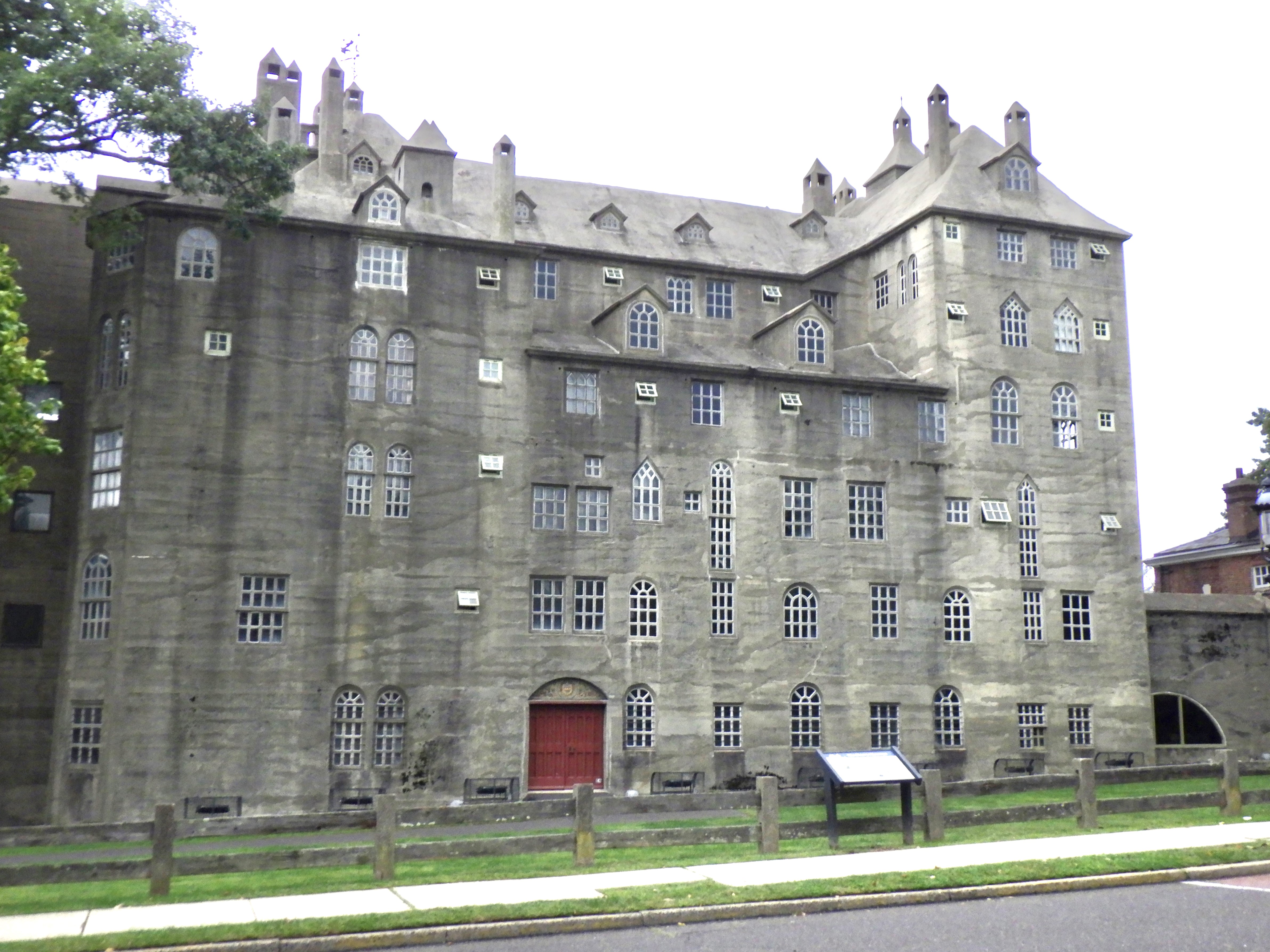 Castle-like stone museum building with Gothic details, red door, and wooden fence.