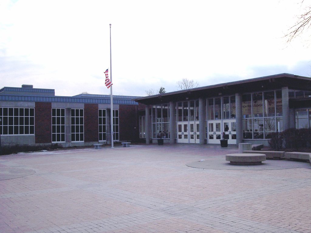 Exterior of Greenwich High School with brick facade, glass entrance, and flagpole