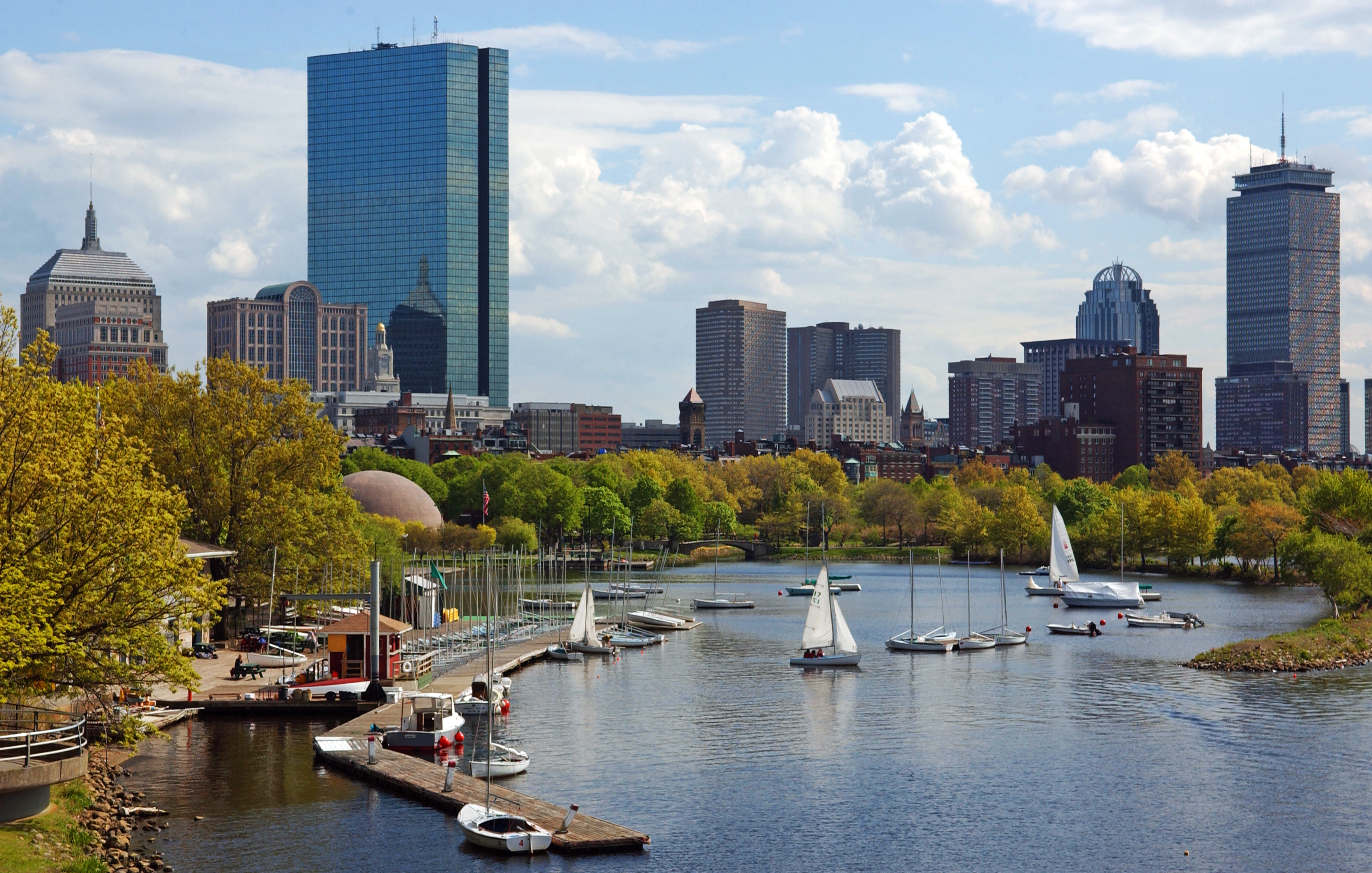 Sailboats and docks on the Charles River with Boston's Back Bay skyline in the background.