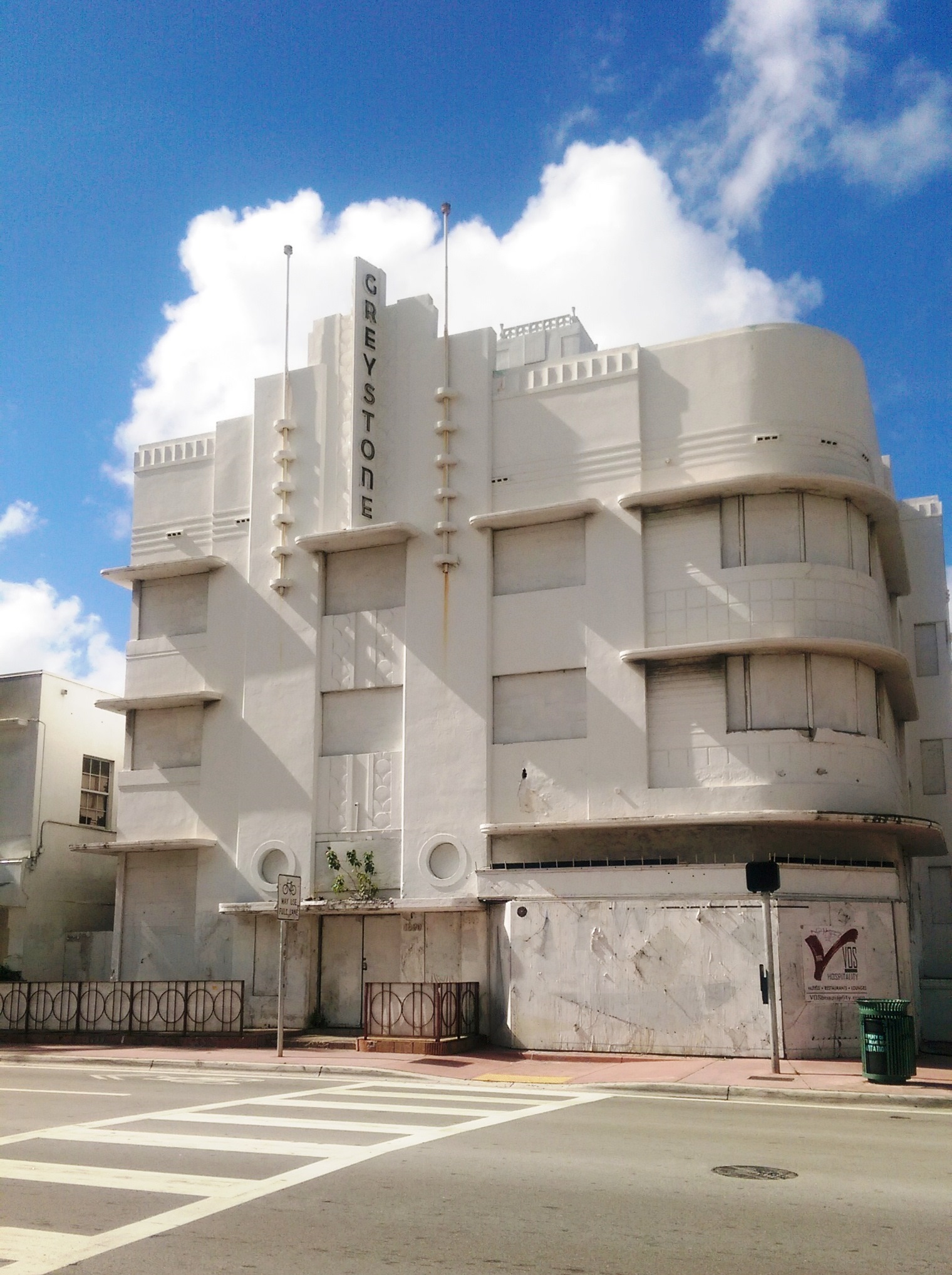 White Art Deco hotel facade on Collins Avenue in South Beach on a sunny day.