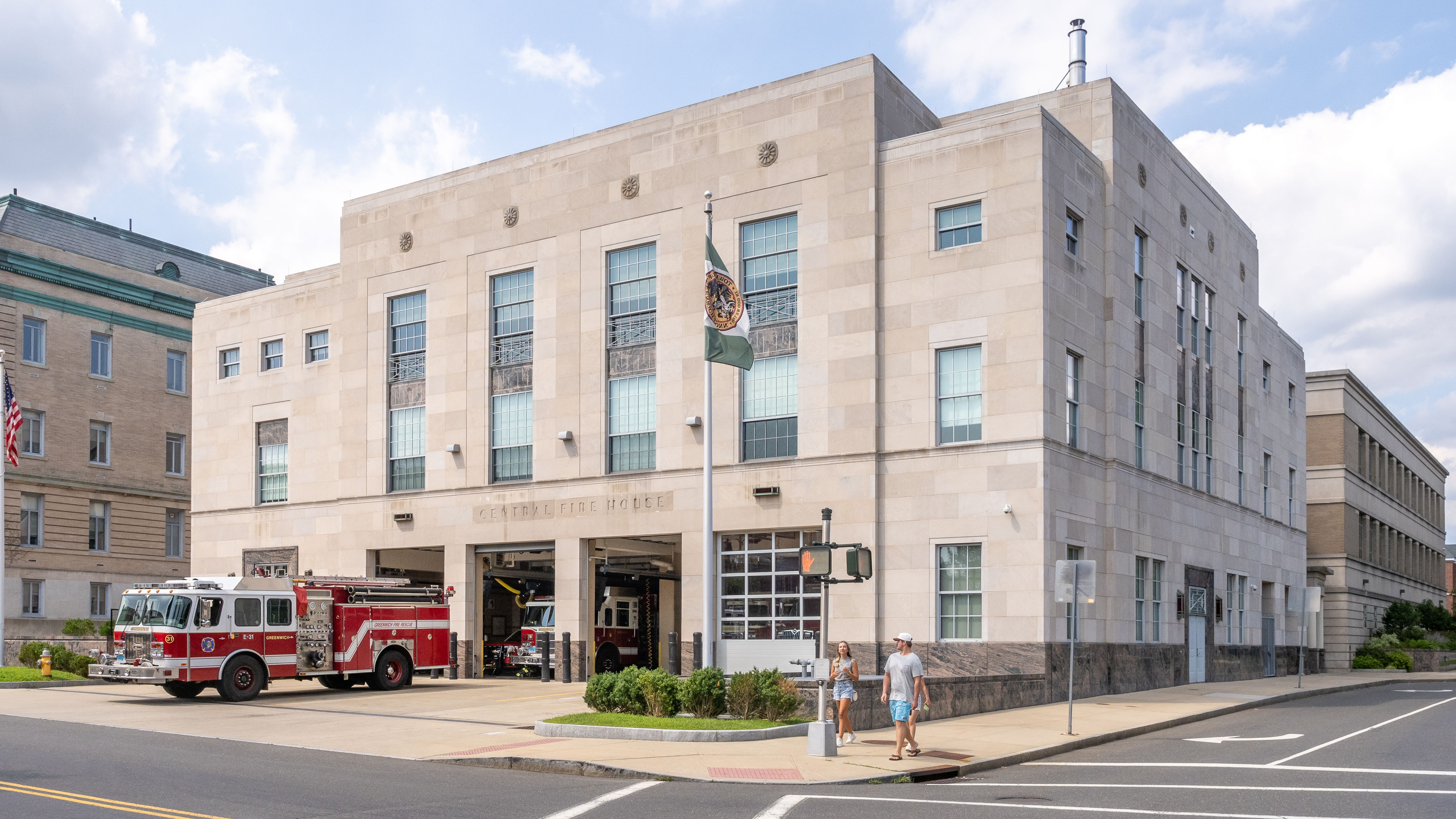 Multi-story stone fire station building with a red fire truck visible in the open apparatus bay.