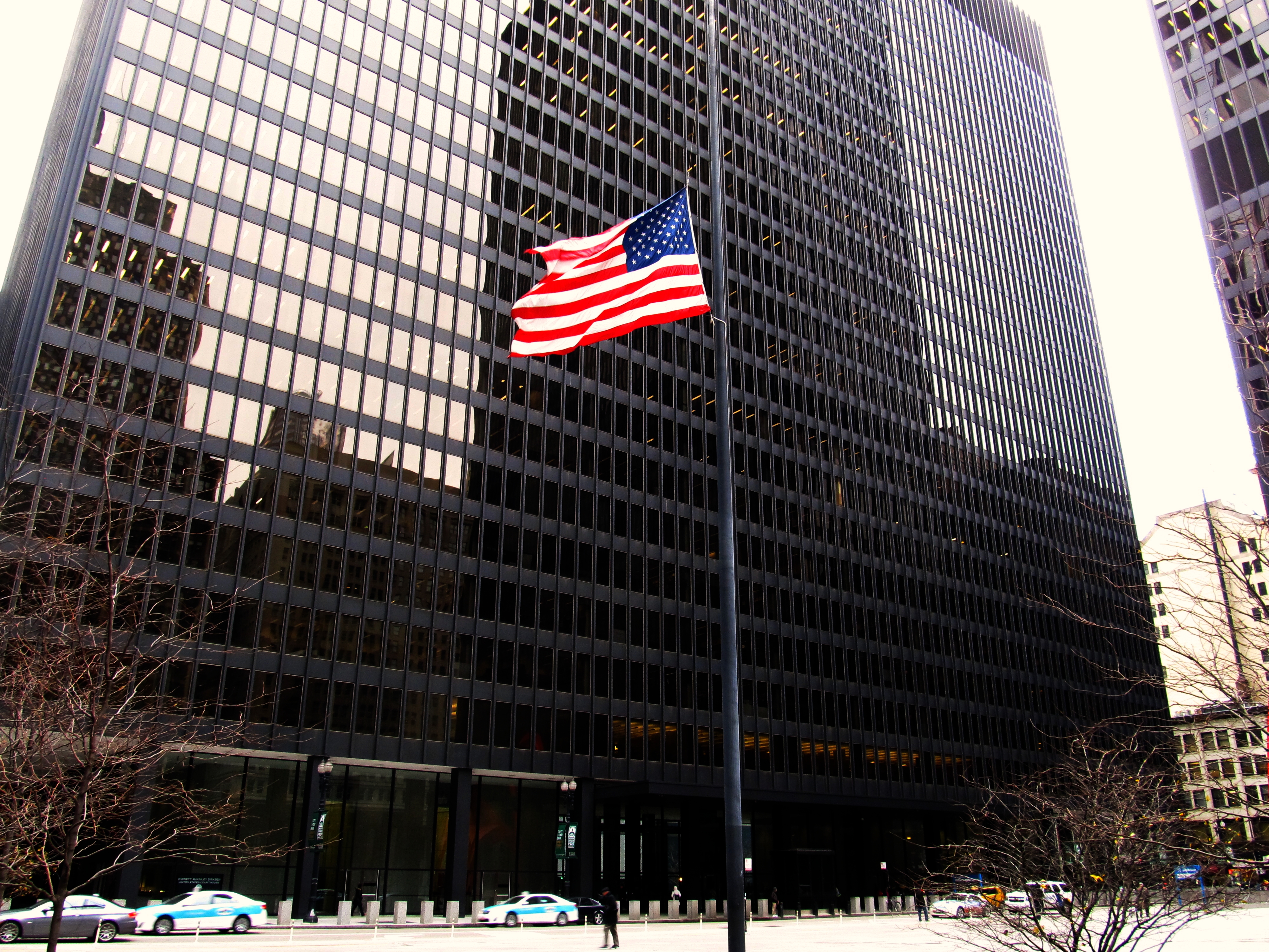Tall modernist glass-and-steel federal courthouse with an American flag and bare winter trees in front.
