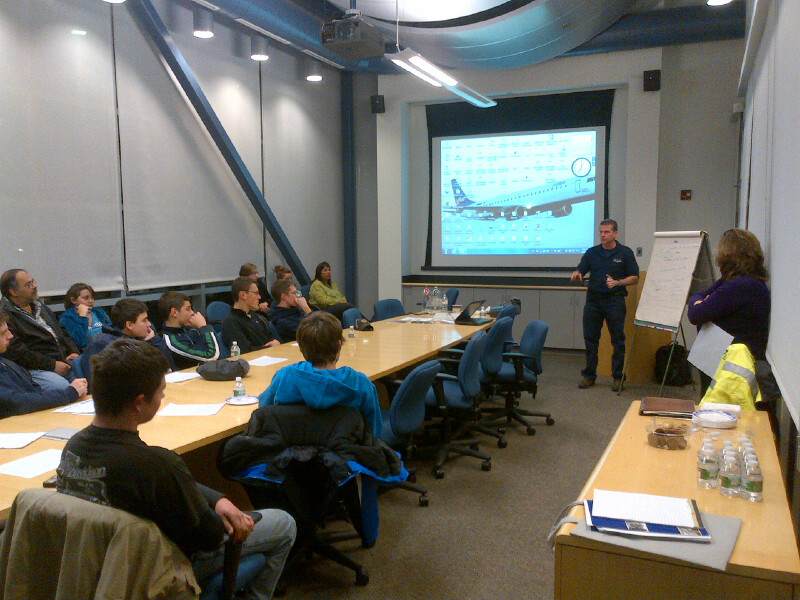 Students seated in a group listen to an instructor at a career exploration event.