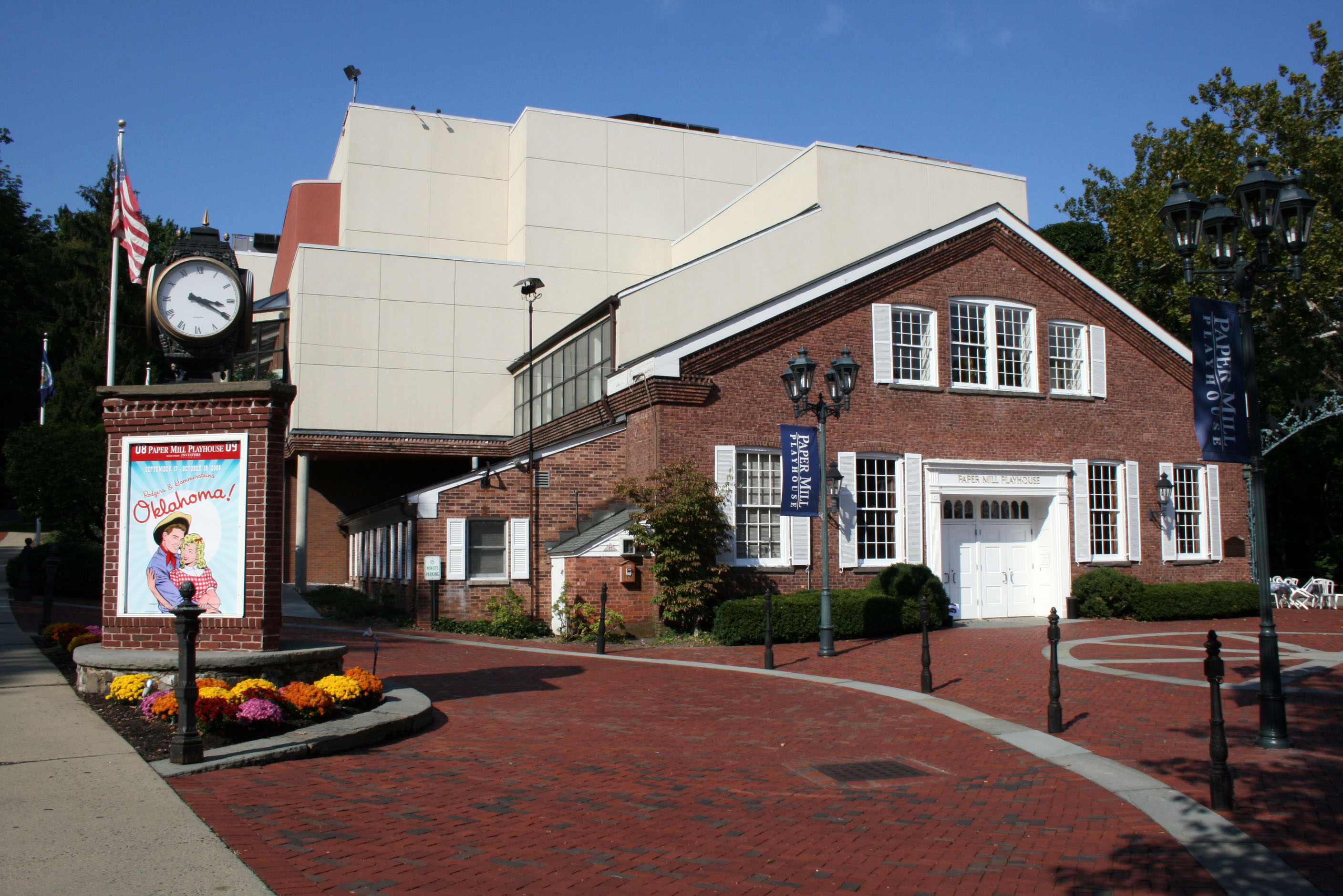Brick entrance of Paper Mill Playhouse with a clock tower and landscaped walkway.