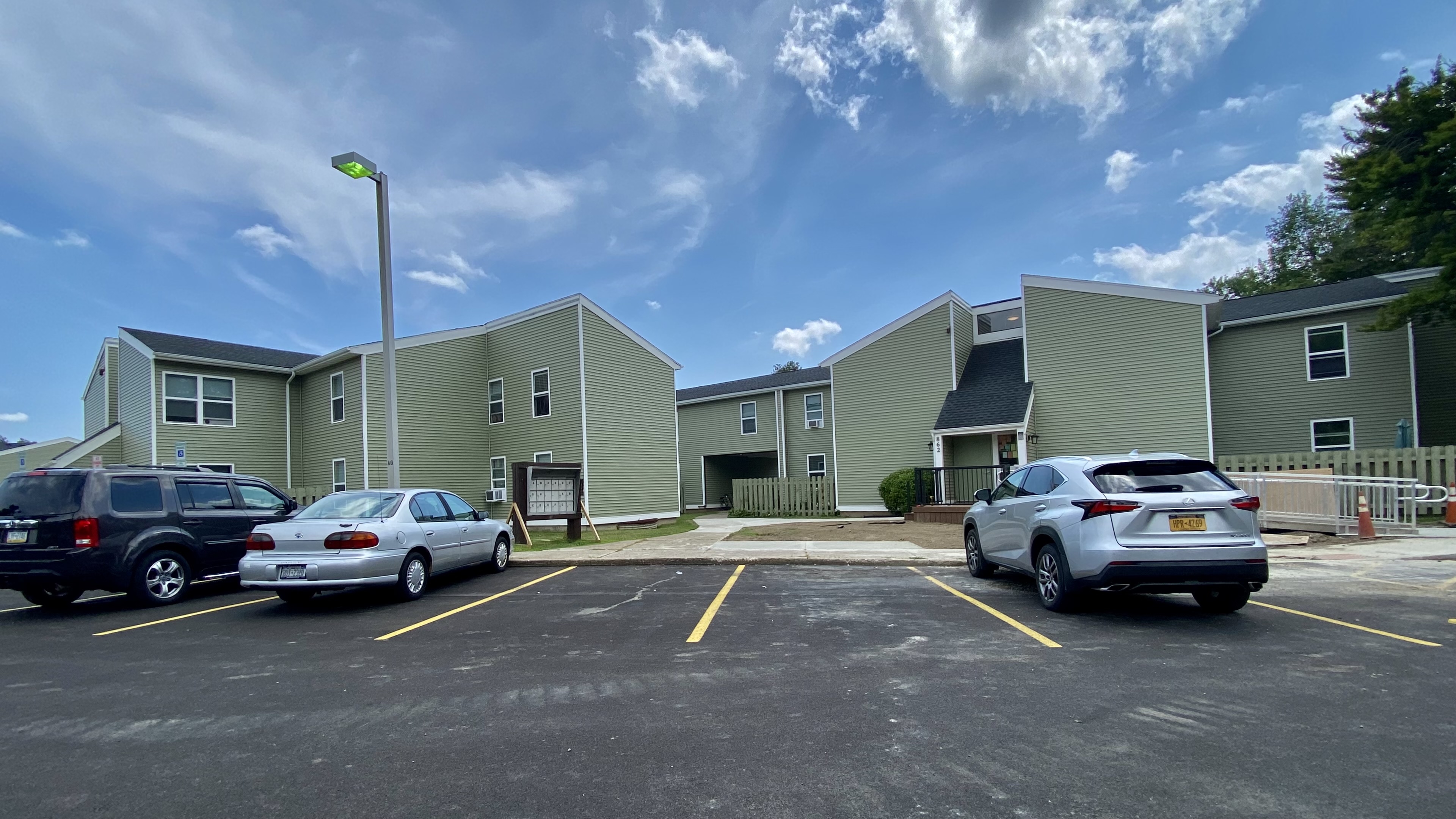 Two-story apartment buildings with green siding and a paved parking lot.