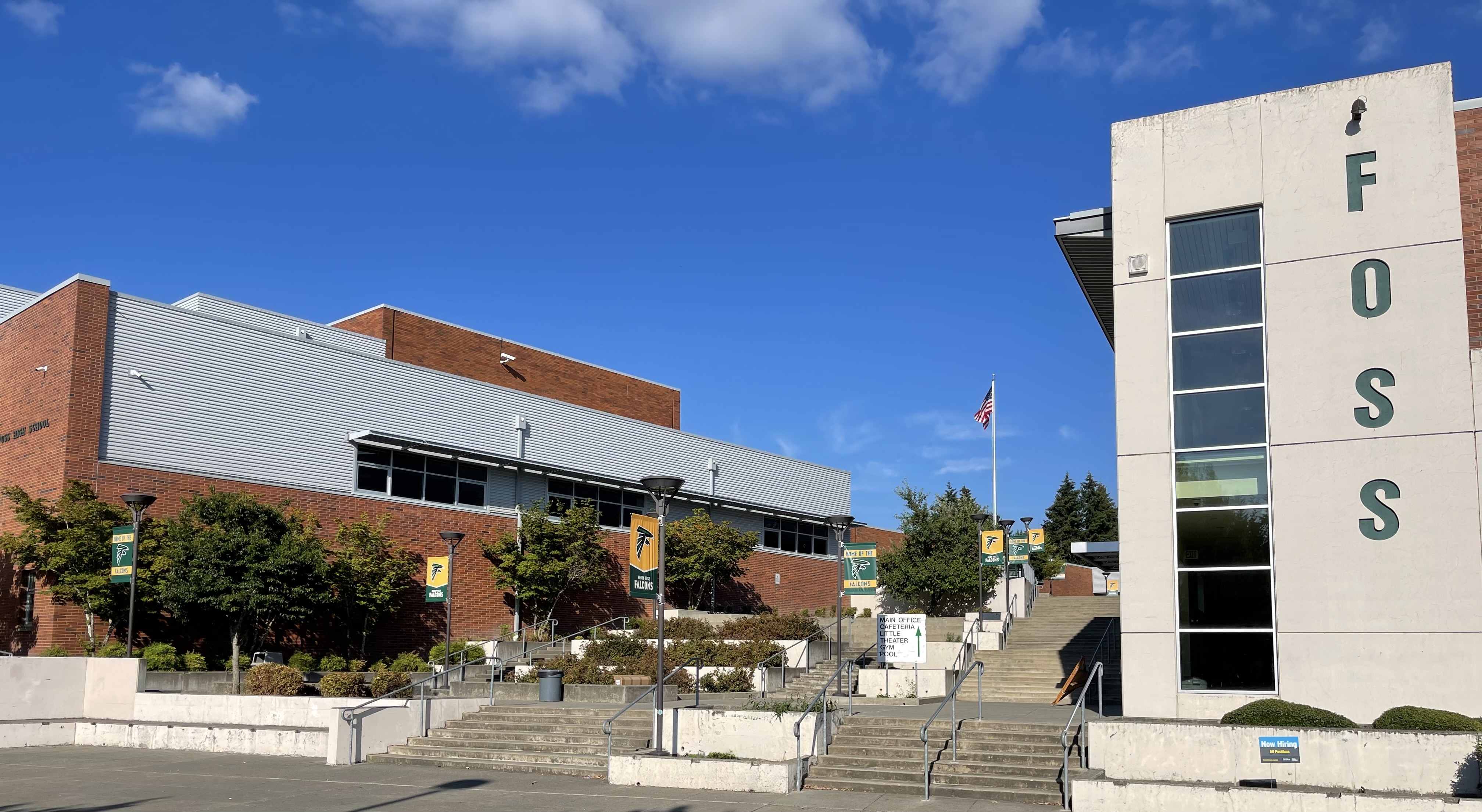 Exterior of a high school campus with a concrete tower spelling out F-O-S-S and a flagpole.
