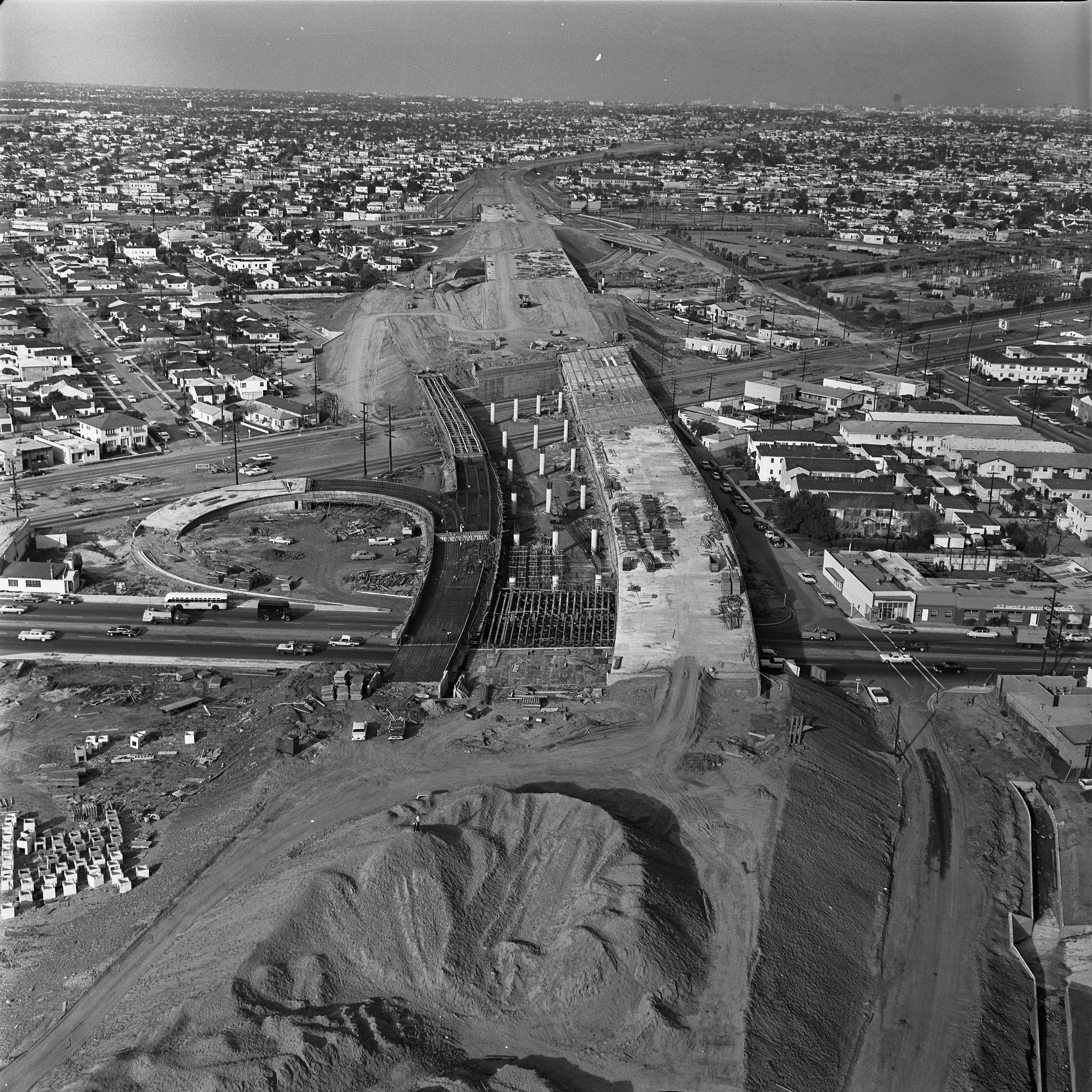 Aerial black-and-white photo of freeway construction cutting through residential neighborhoods with off-ramps being built.