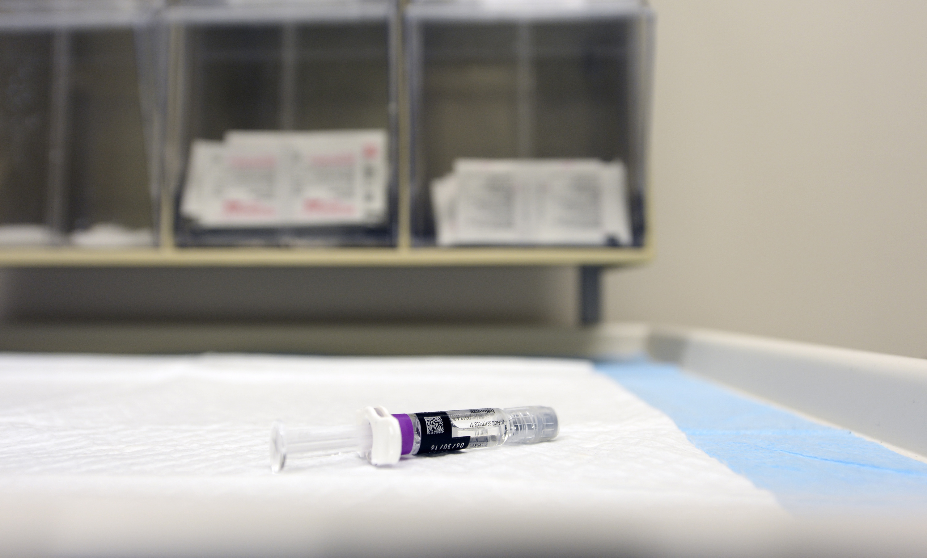 A single-dose flu vaccine syringe resting on a sterile medical pad.