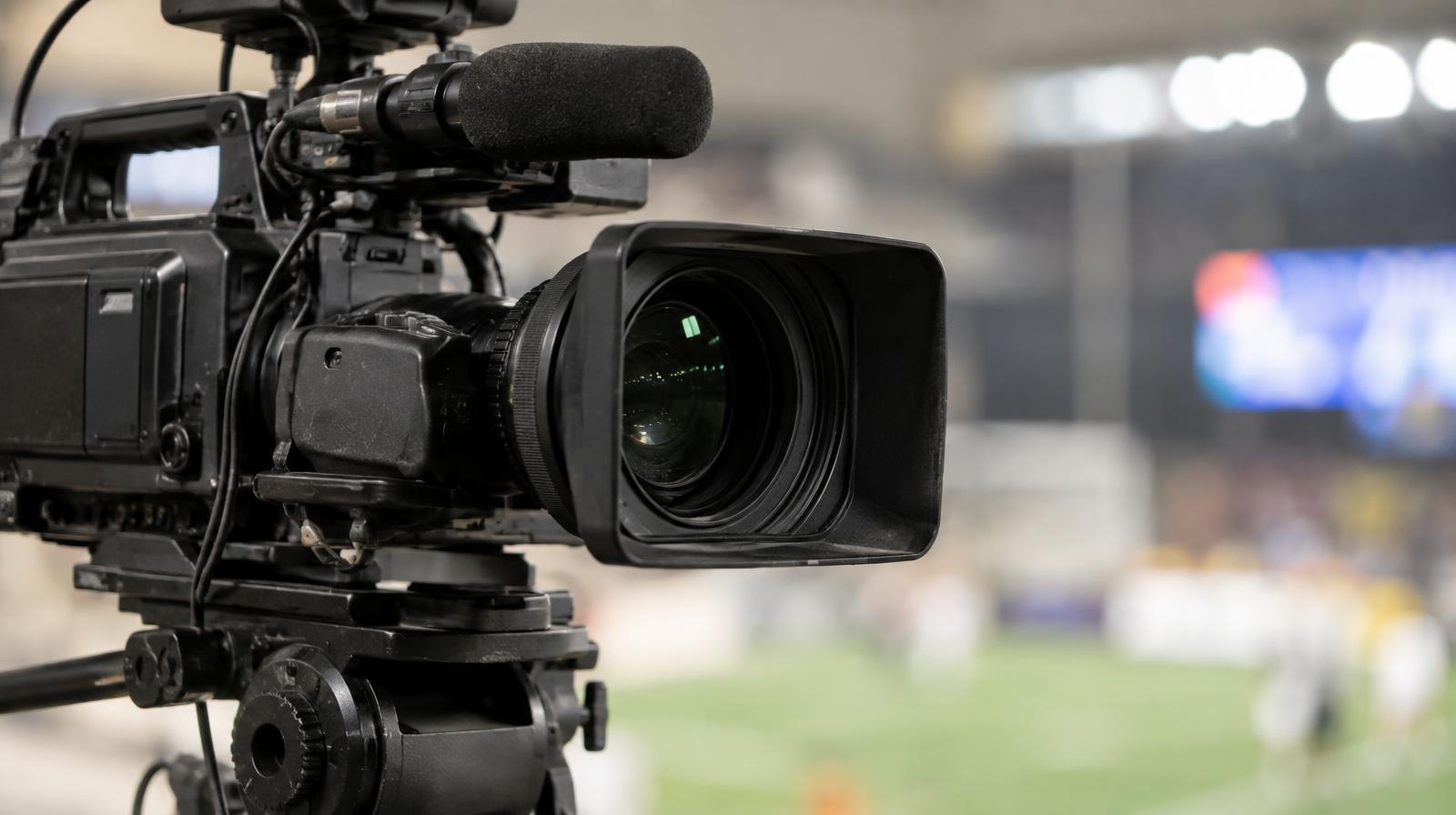 Professional broadcast television camera mounted on a tripod under studio lighting.