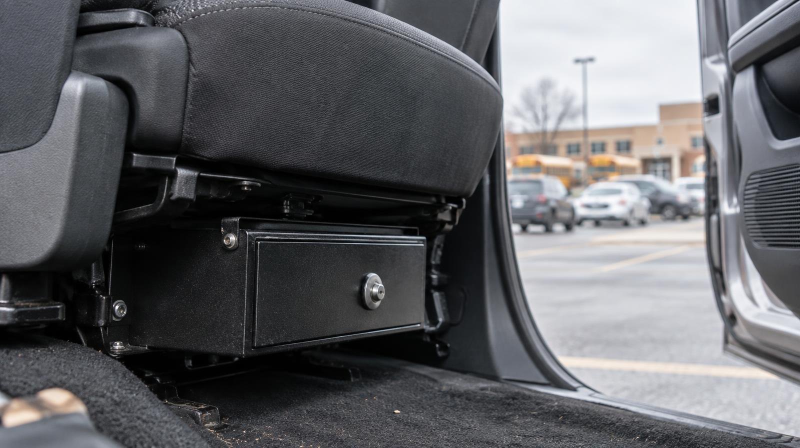 A locked metal gun safe mounted under a car seat, door open.