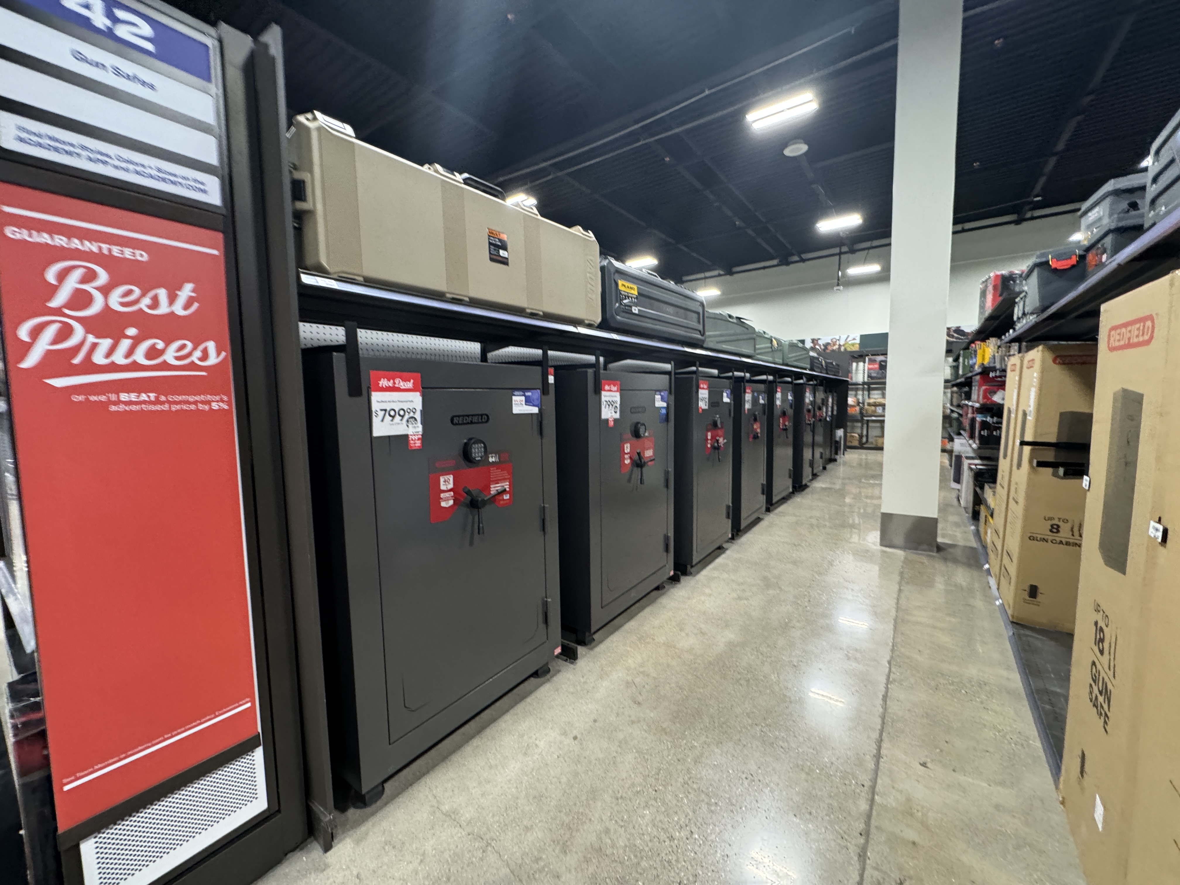 A row of large dark-colored gun safes on display in a retail store.