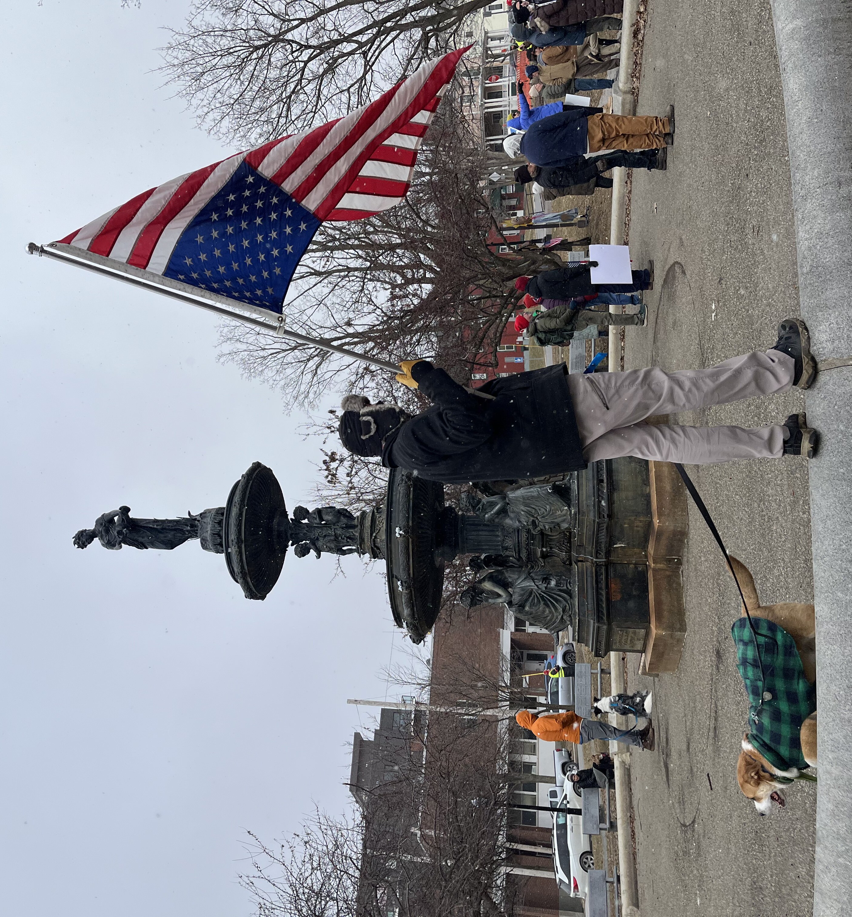 A person holds an upside-down American flag at an outdoor gathering.