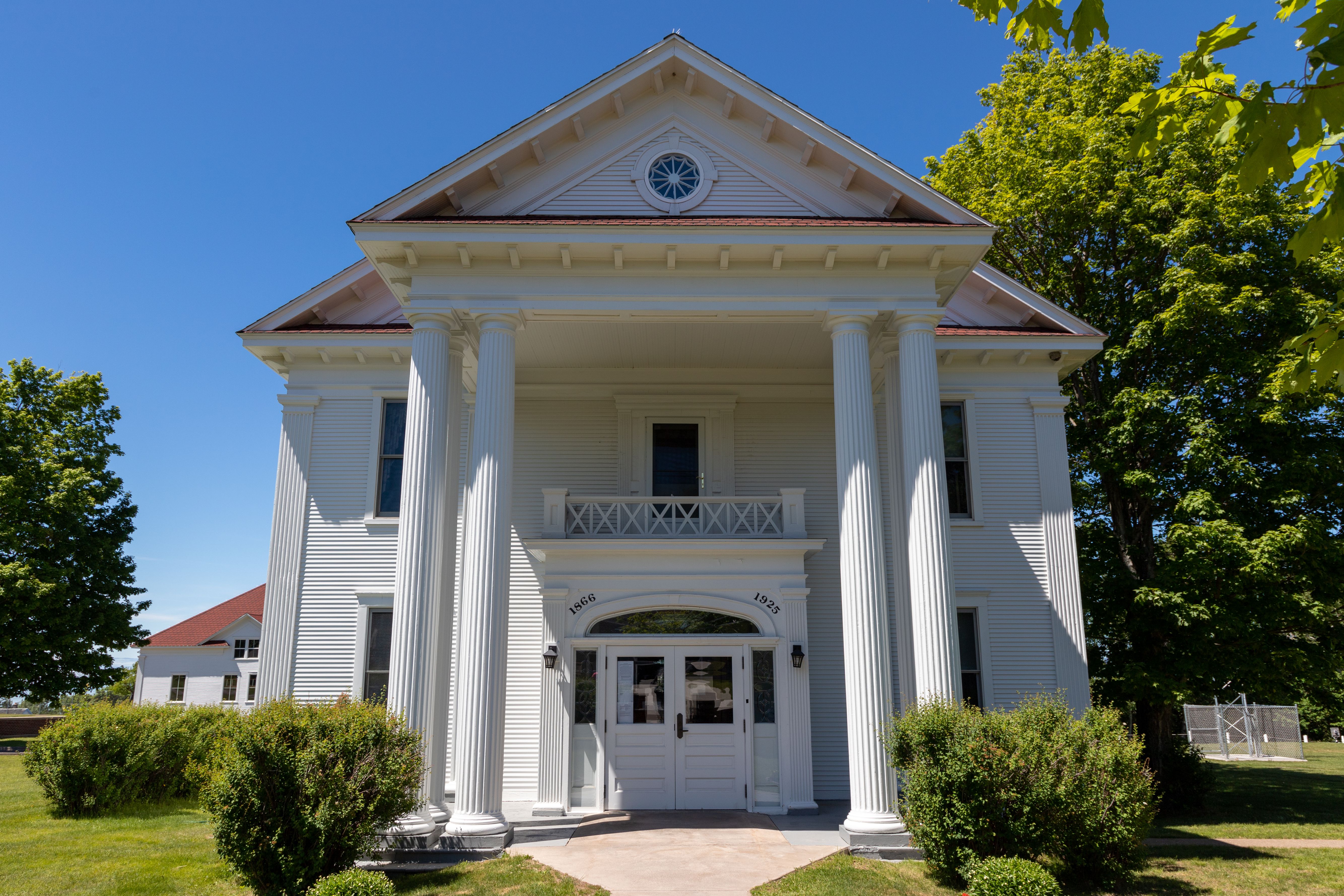 White Greek Revival courthouse with tall Doric columns and a circular pediment window.
