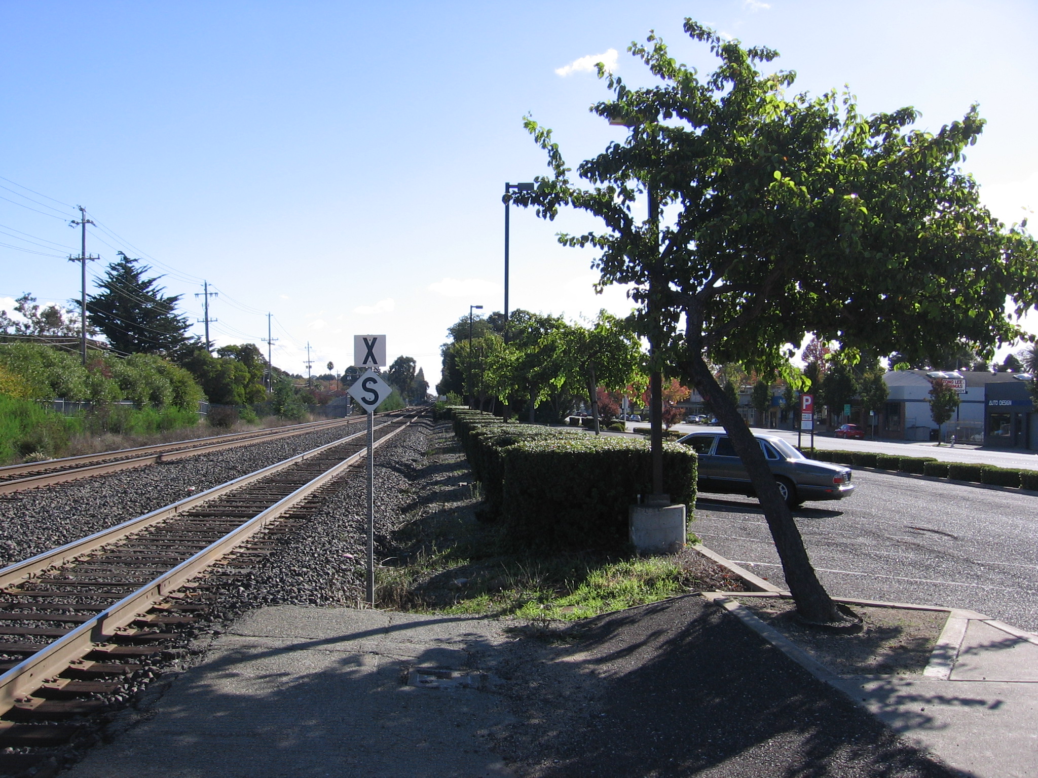 Railroad tracks at an at-grade crossing with a crossbuck warning sign and utility poles.