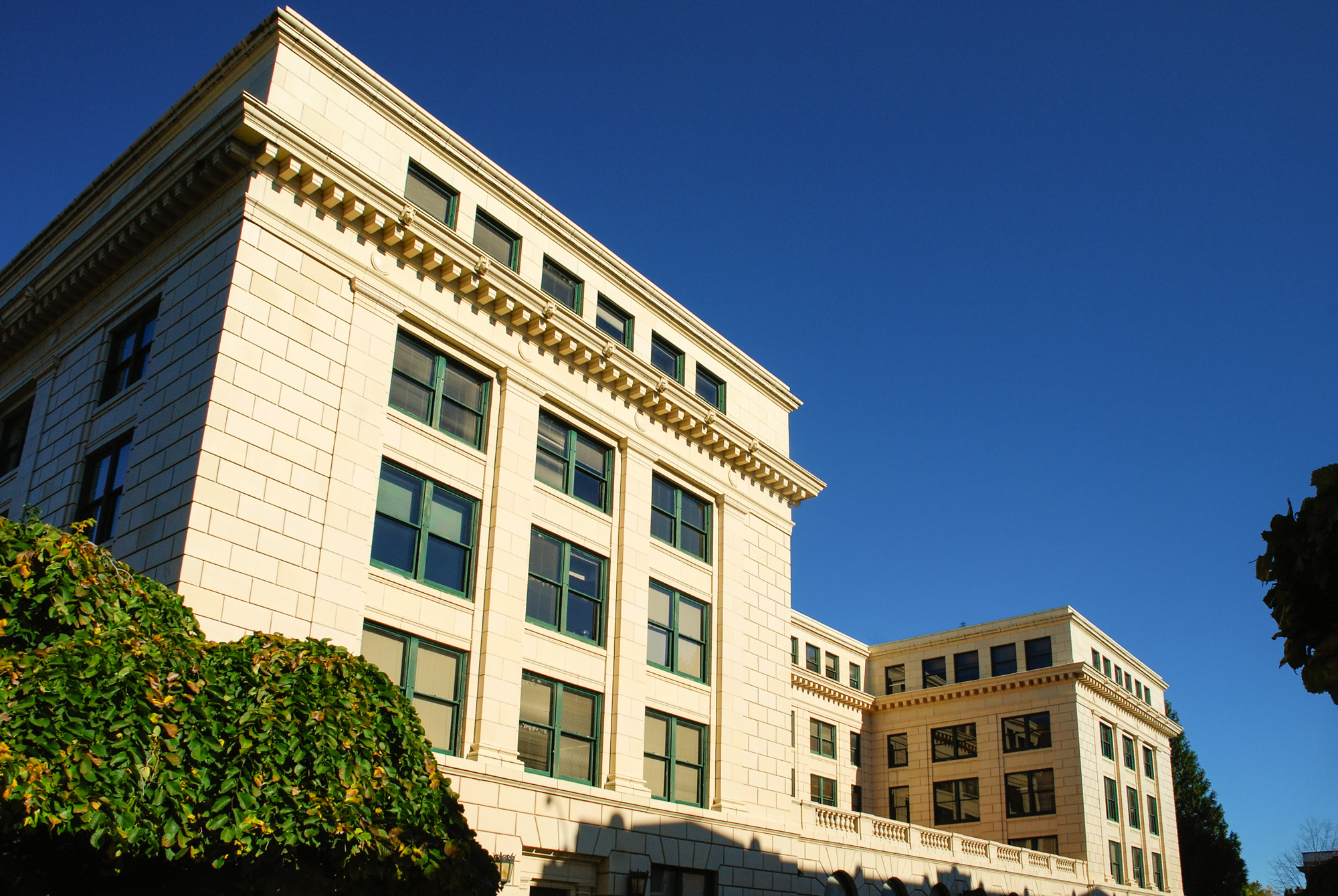 Multi-story neoclassical government building with light stone facade against a blue sky.