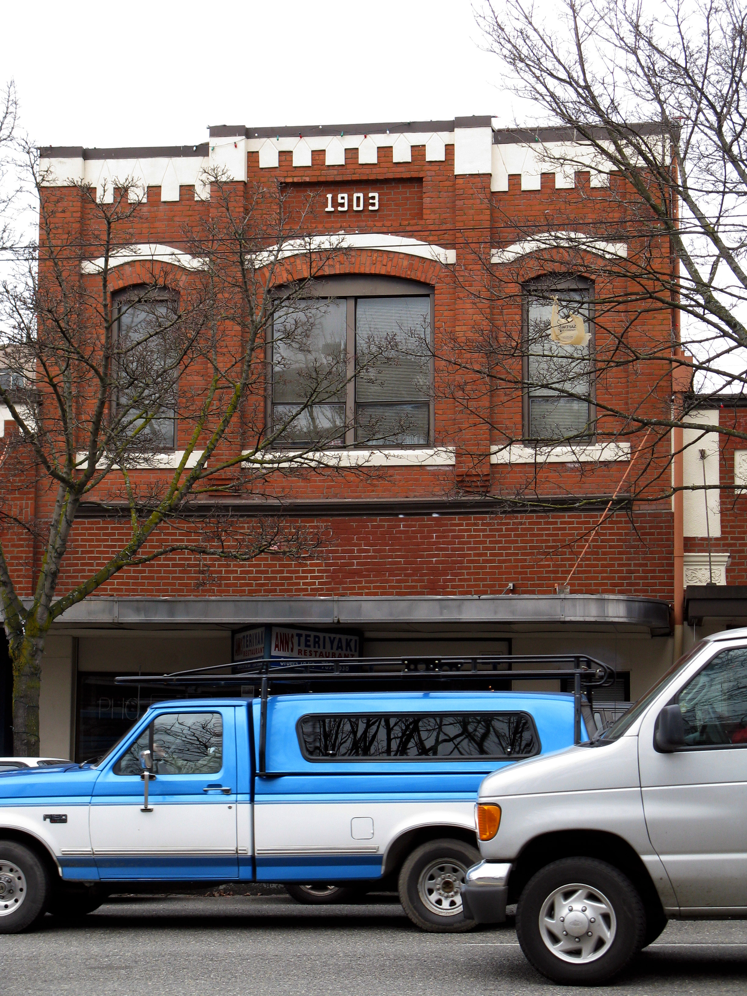 Two-story red brick building with arched upper windows on a Seattle street.