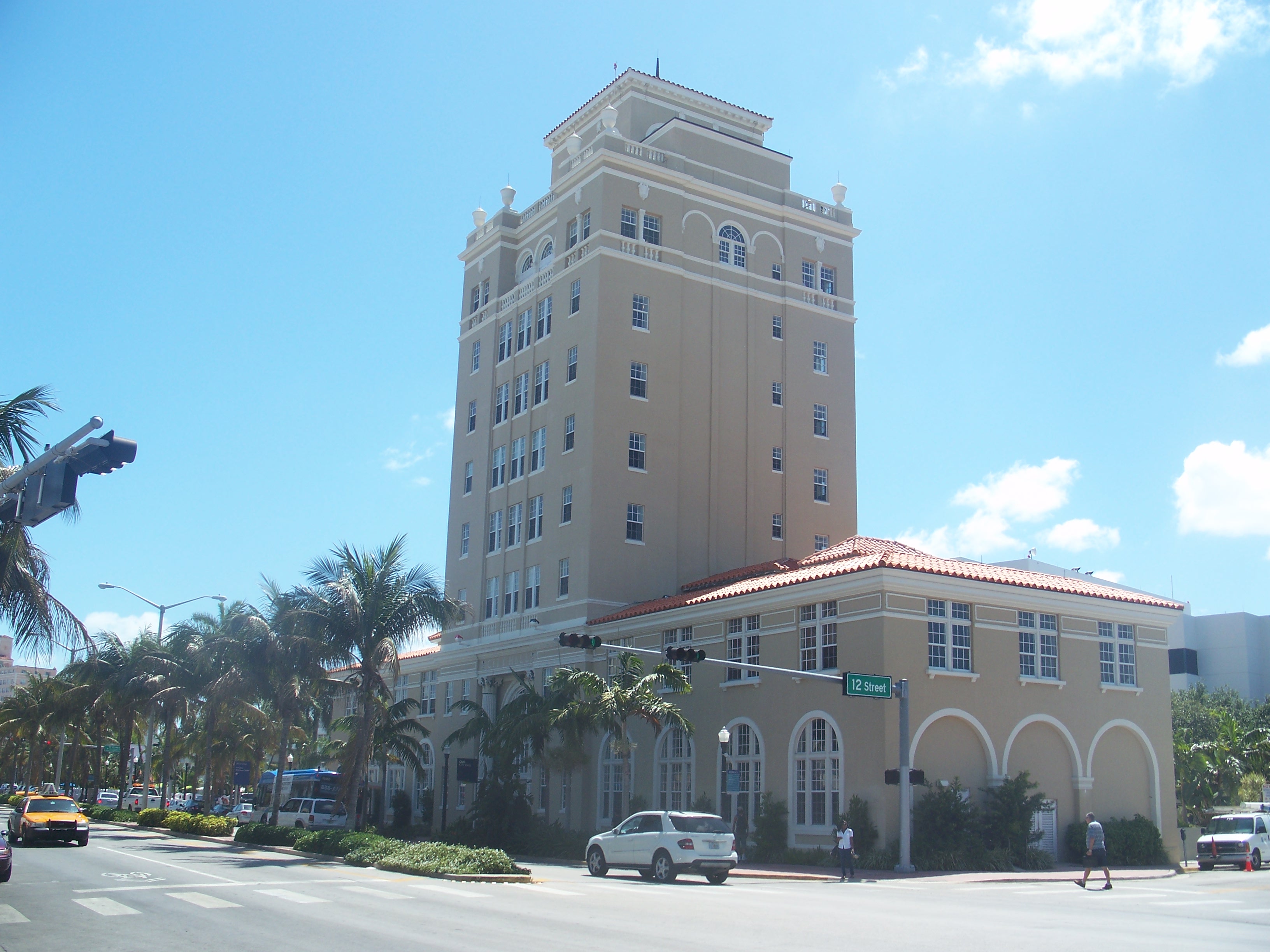 Miami Beach City Hall exterior with tall tower, arched windows, and palm trees.