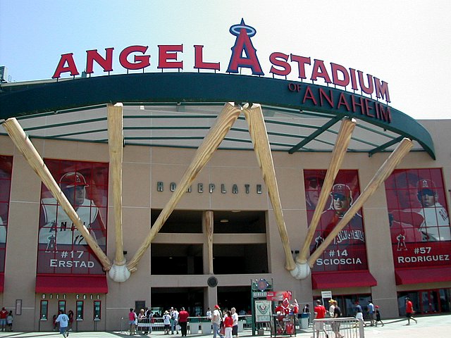 Exterior entrance of a baseball stadium with large decorative crossed bats and player banners.