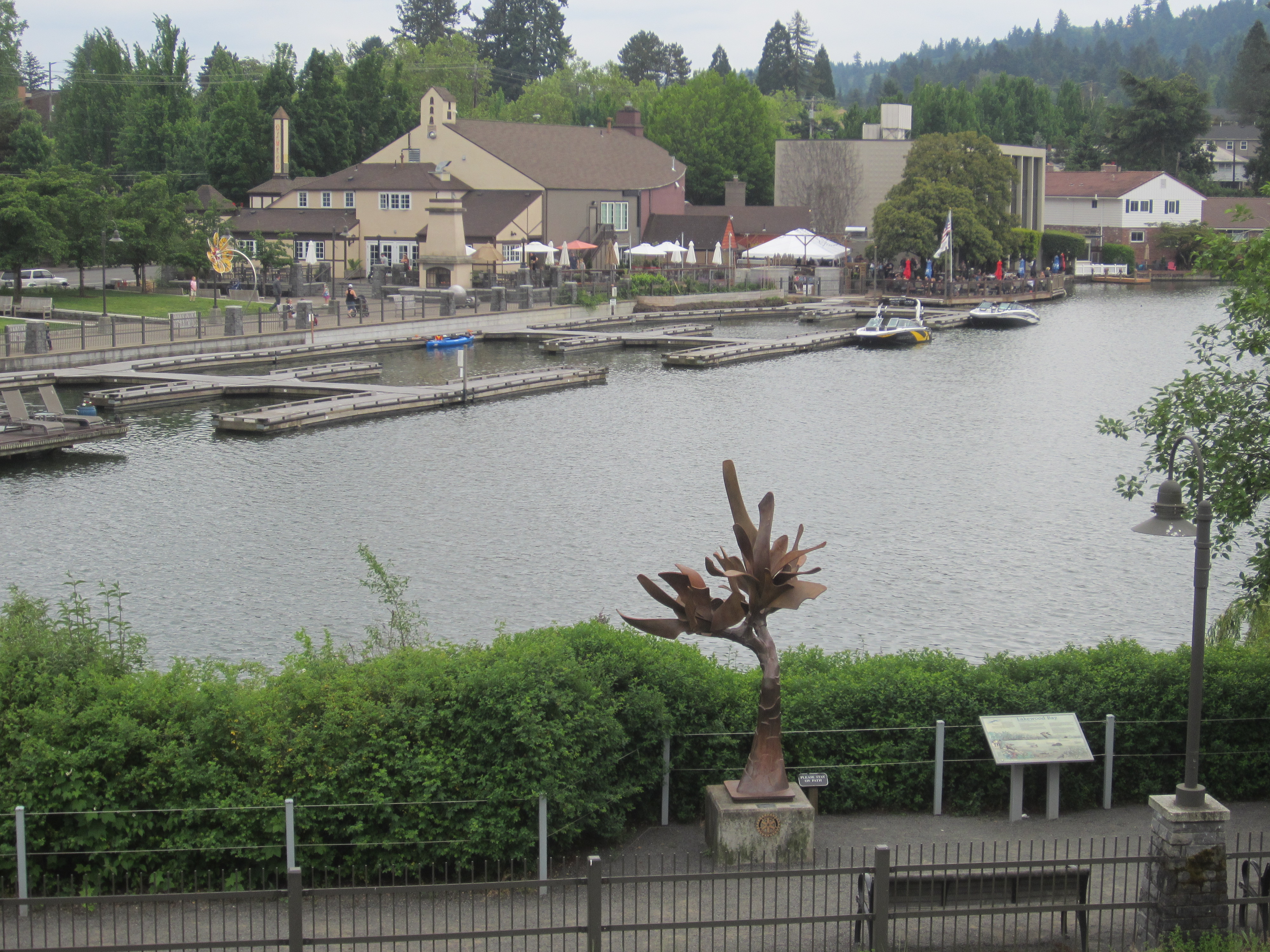 Calm lake with docked boats at a small marina, buildings lining the far shore.