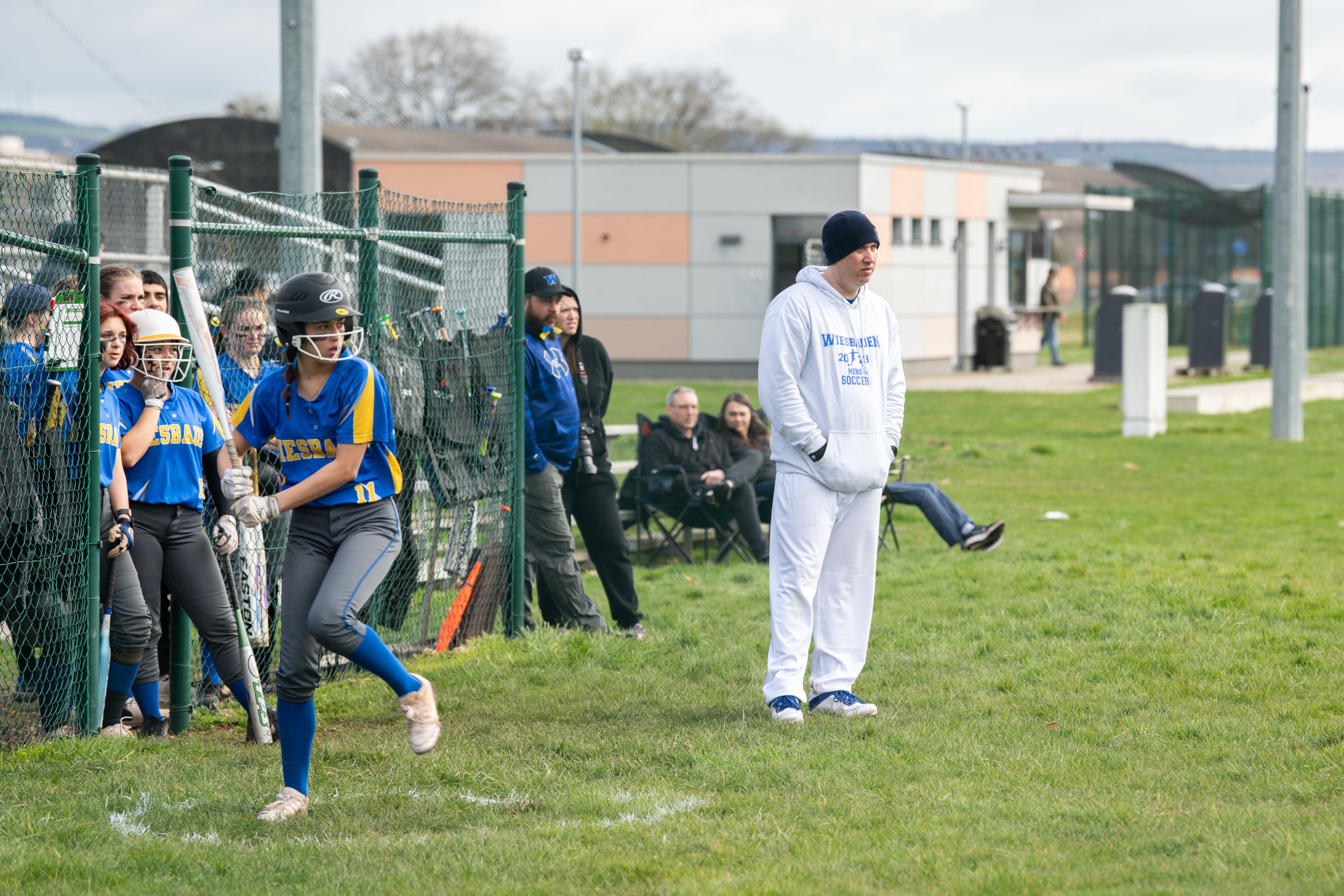 Softball player in uniform prepares to bat on a grass field.