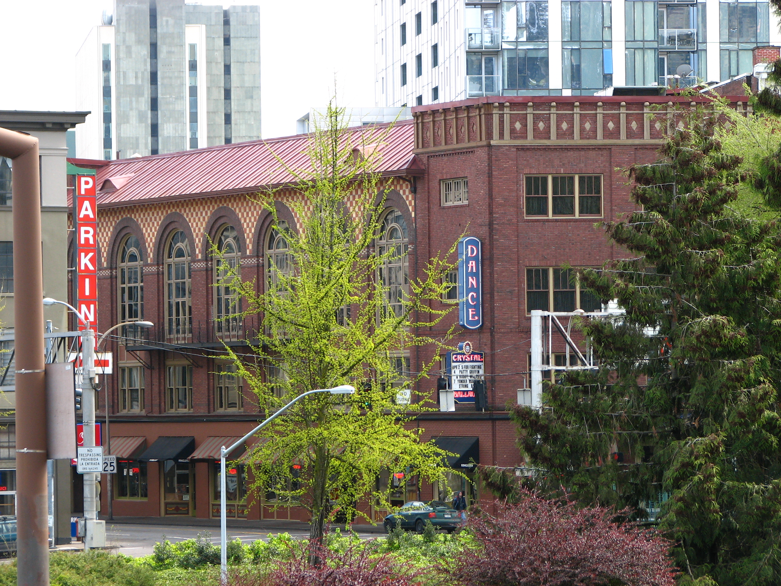 Historic red-brick concert hall with a vertical neon 'DANCE' sign on its facade.