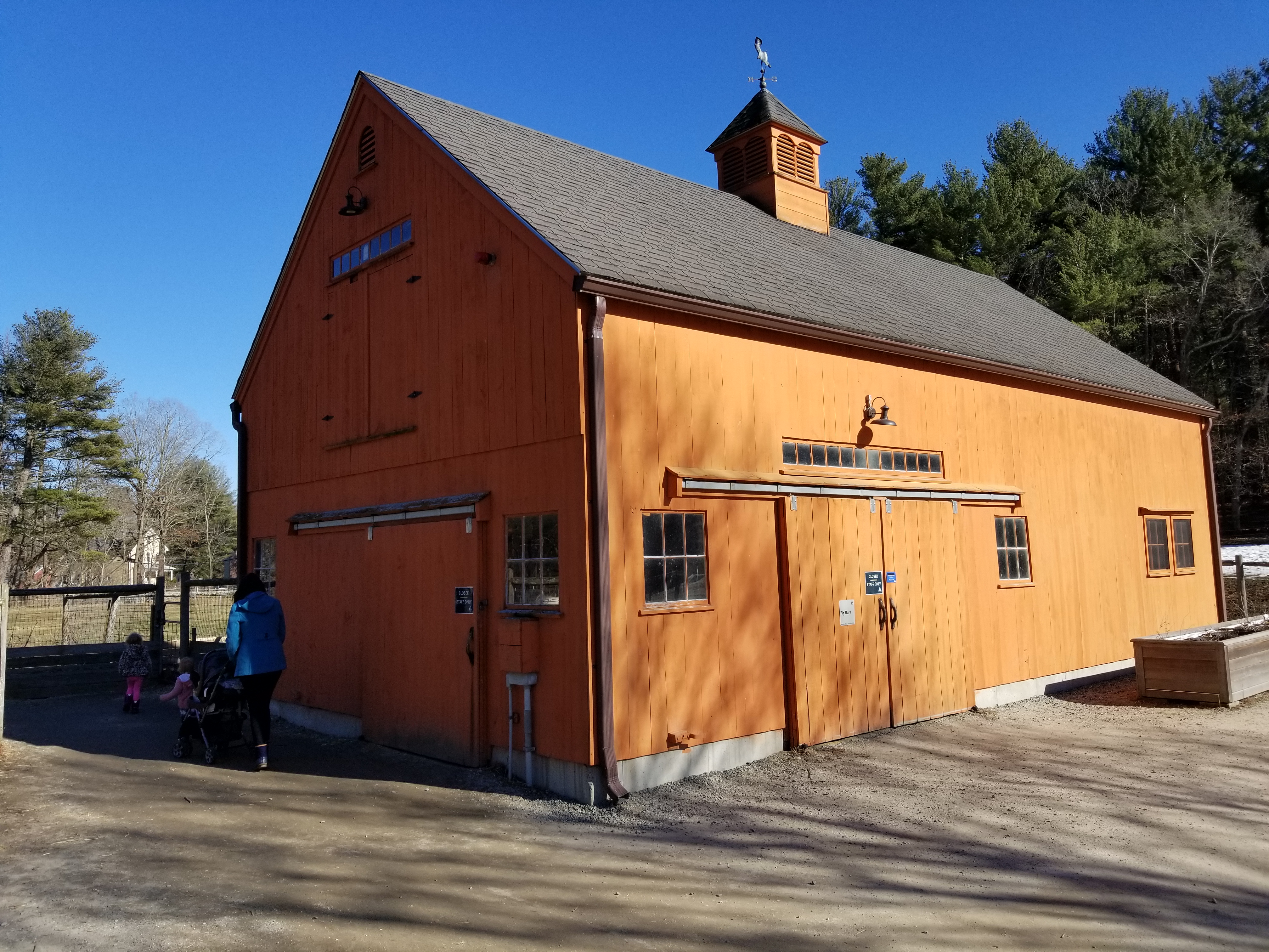 Large orange barn with gambrel roof at a farm wildlife sanctuary on a sunny day.