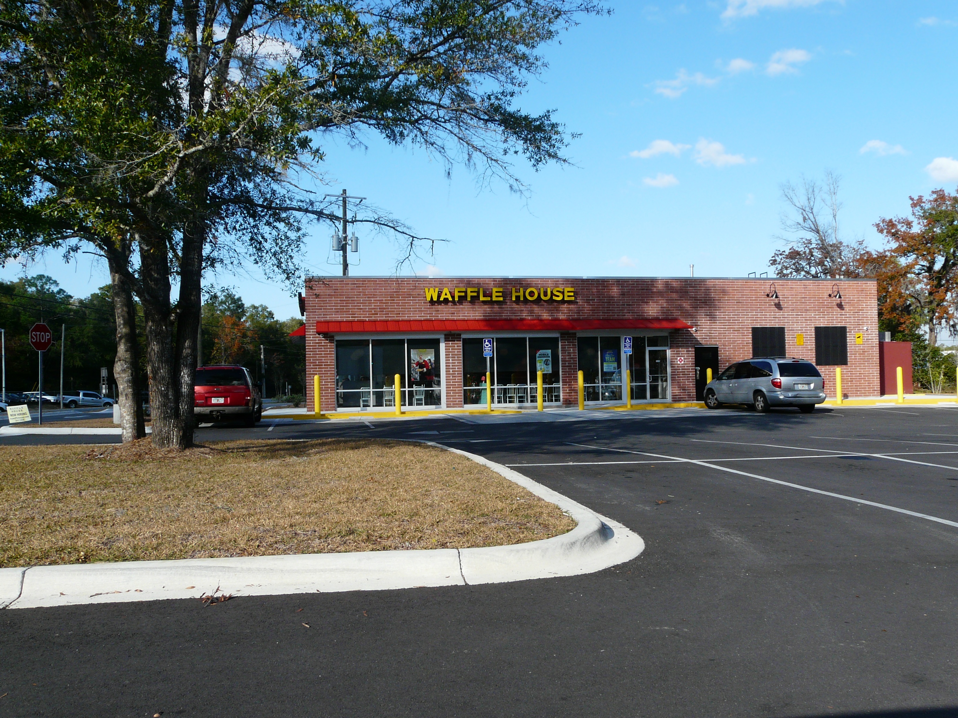 Brick Waffle House restaurant exterior with yellow sign and red awning.