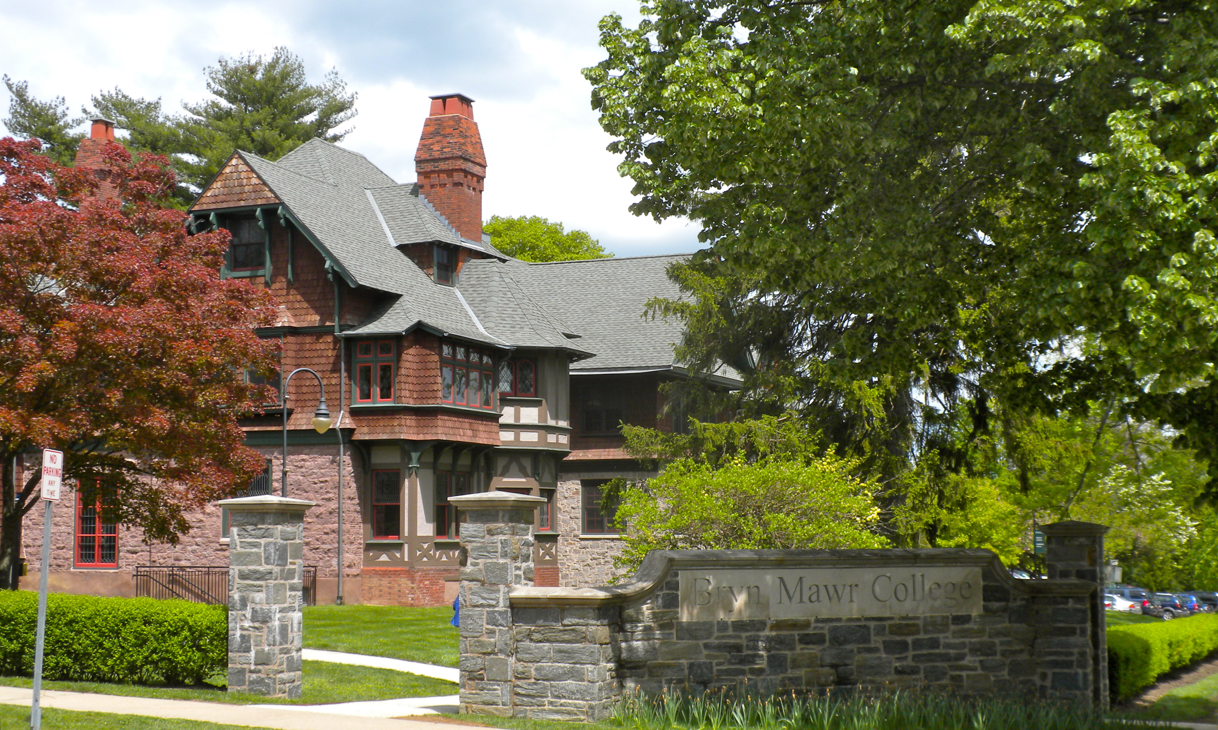 Stone entrance pillars and a historic brick building at a college campus entrance.