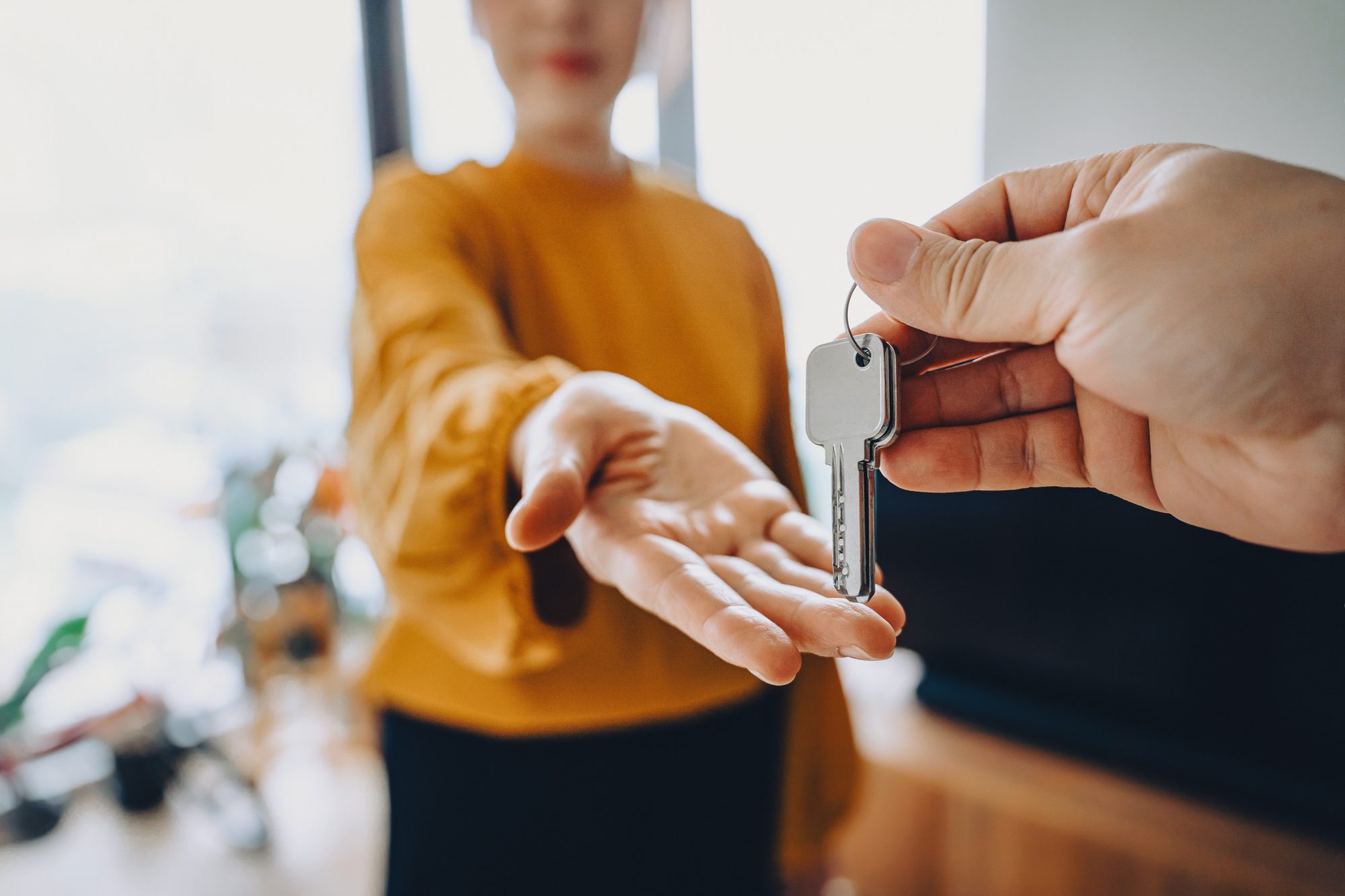 Close-up shot of a real estate agent giving a young Asian woman the keys to her new home. Home ownerships concepts