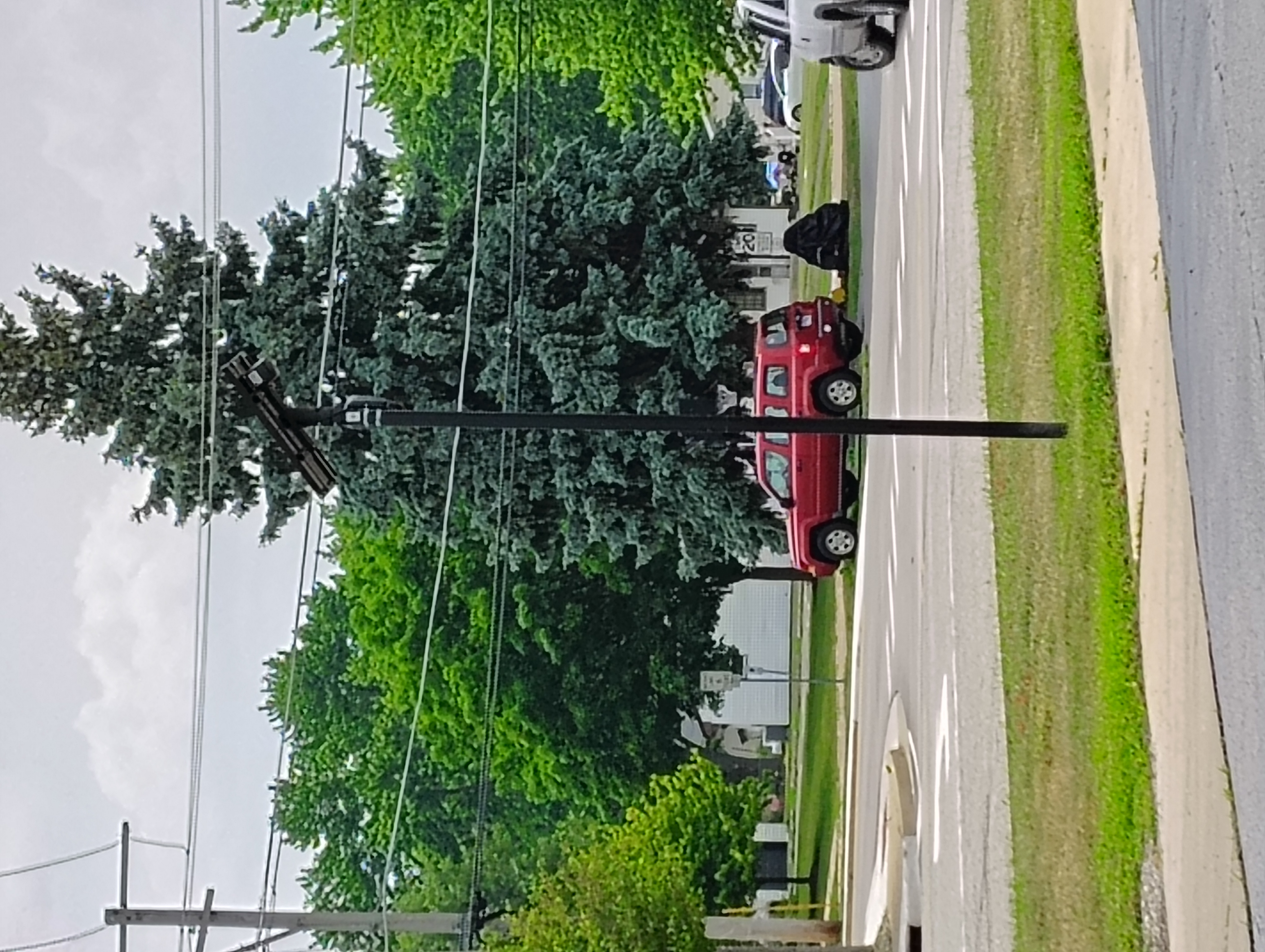 A Flock Safety ALPR camera with solar panel on a pole at a street intersection.