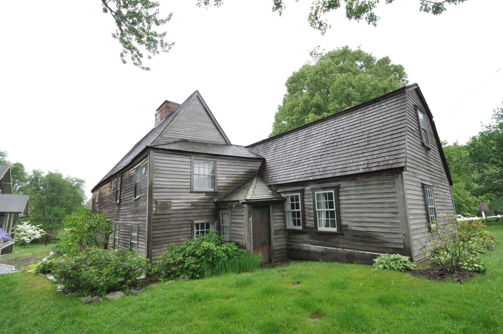 Weathered colonial timber-framed house with aged cedar shingle roof and multiple gabled sections.