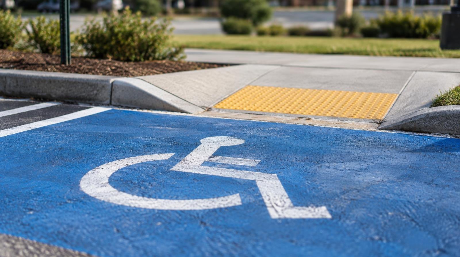 Blue accessible parking space with wheelchair symbol painted on pavement beside a curb cut.